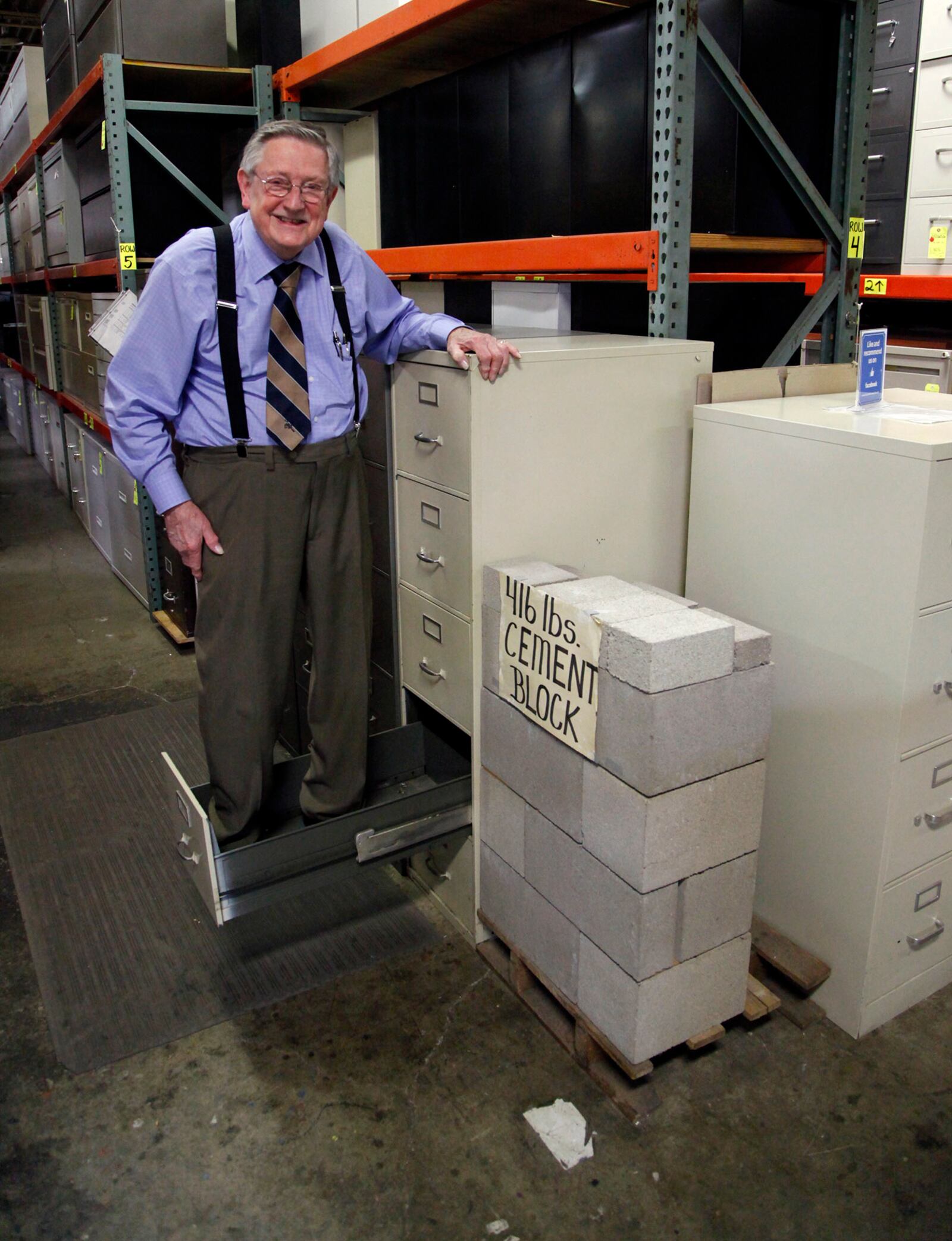 Charles Larrick in his furniture warehouse demonstrates the strength of a file cabinet by standing in the drawer with his 190 lb. frame. TY GREENLEES / STAFF