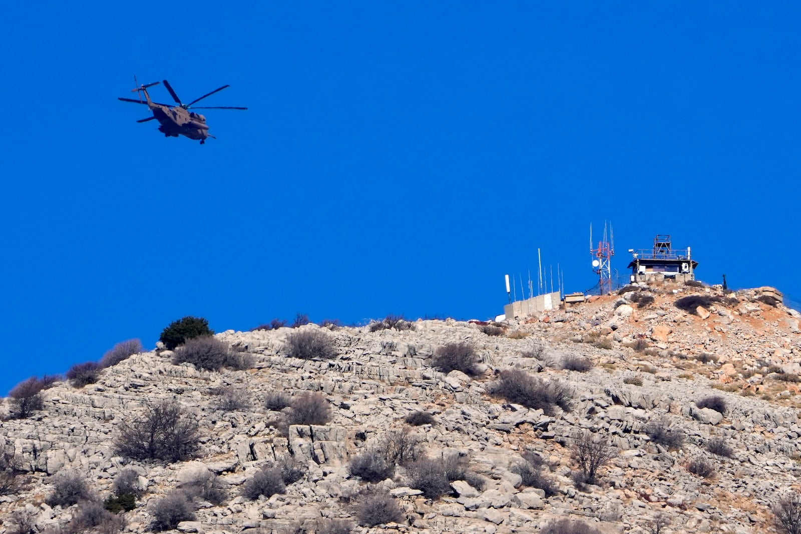 An Israeli Air Force Black Hawk helicopter flies over Mount Hermon, near the so-called Alpha Line that separates the Israeli-controlled Golan Heights from Syria, viewed from the town of Majdal Shams, Tuesday, Dec. 17, 2024. (AP Photo/Matias Delacroix)