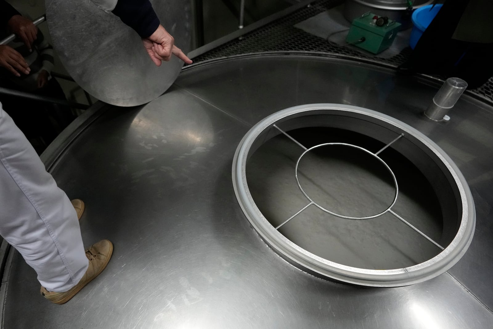 A worker for Ozawa Sake Brewery opens a lid of a tank to show sake being fermented during a media tour at the brewery in Ome, on the western outskirts of Tokyo, Japan, Wednesday, Nov. 13, 2024. (AP Photo/Hiro Komae)