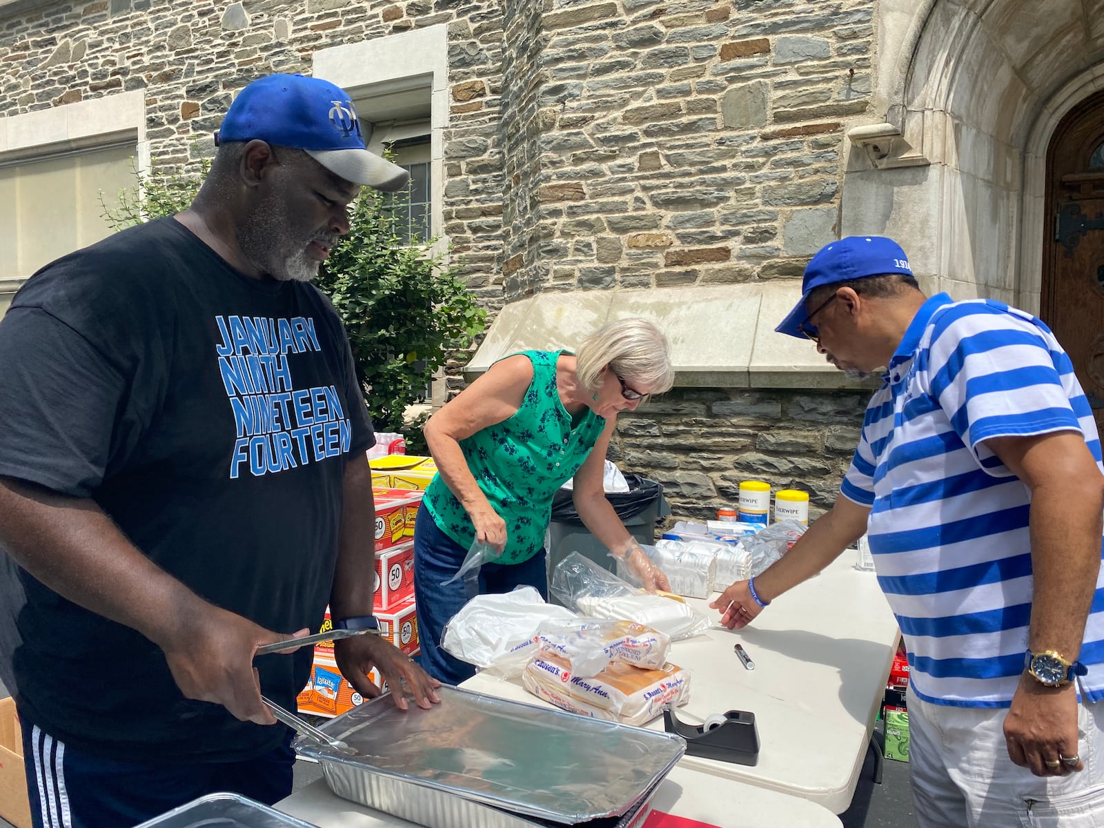 Keith Perkins, at right, gets a hot dog from Ted Clark, far left and Shirley Mell, center, at the Grace United Methodist Church 100th anniversary celebration on Saturday.  Eileen McClory / Staff