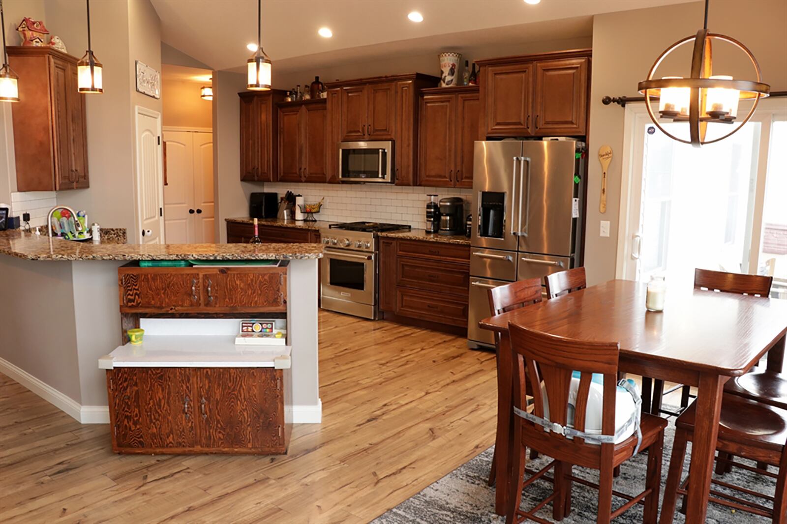 A 2-level peninsula countertop divides the kitchen from the great room and wraps around into the dining area. The lower countertop surrounds the double sink and offers plenty of preparation space. Quartz countertops complement the maple cabinetry. Recessed lighting fills the kitchen area. CONTRIBUTED PHOTO BY KATHY TYLER