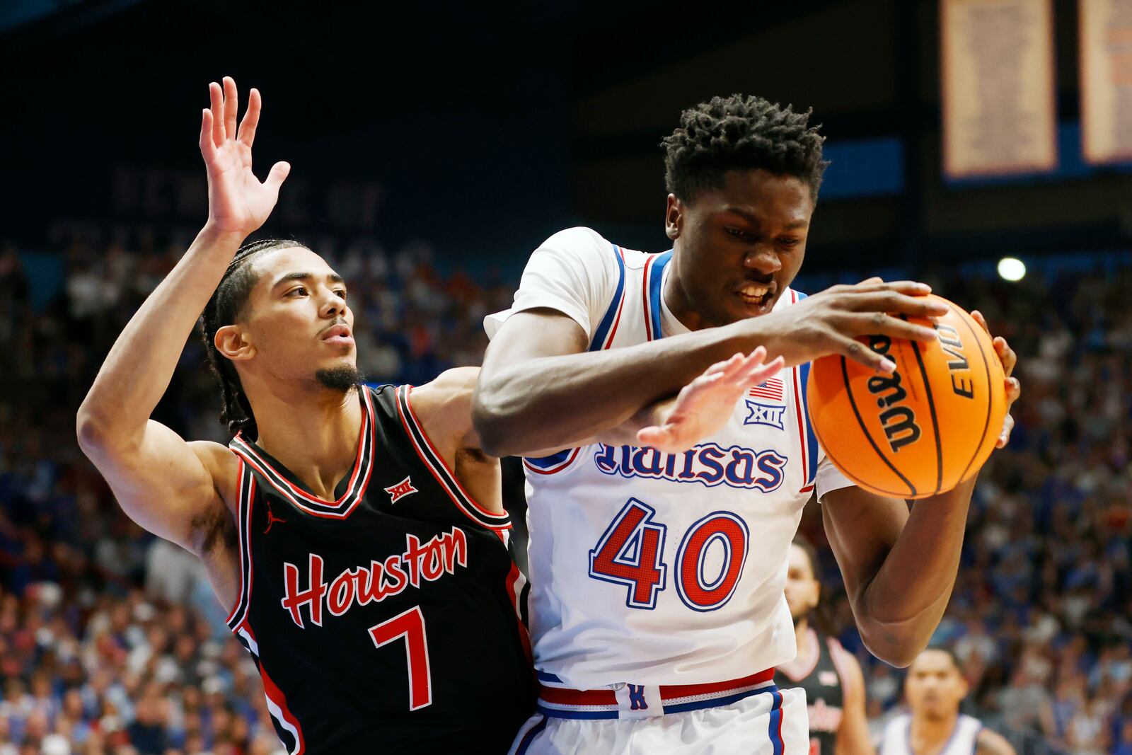 Kansas forward Flory Bidunga (40) grabs a rebound as Houston guard Milos Uzan (7) defends during the first half of an NCAA college basketball game, Saturday, Jan. 25, 2025, in Lawrence, Kan. (AP Photo/Colin E. Braley)