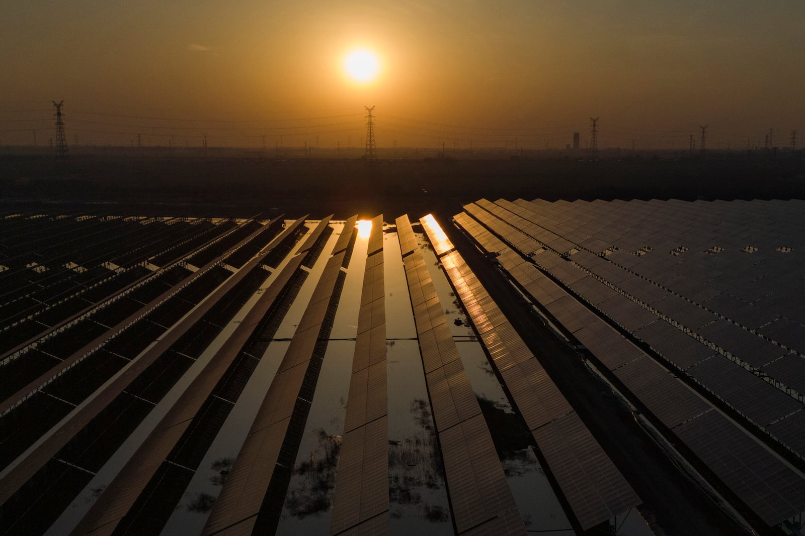 The sun sets over electric pylons along a solar farm near Weifang in eastern China's Shandong province on March 22, 2024. (AP Photo/Ng Han Guan)