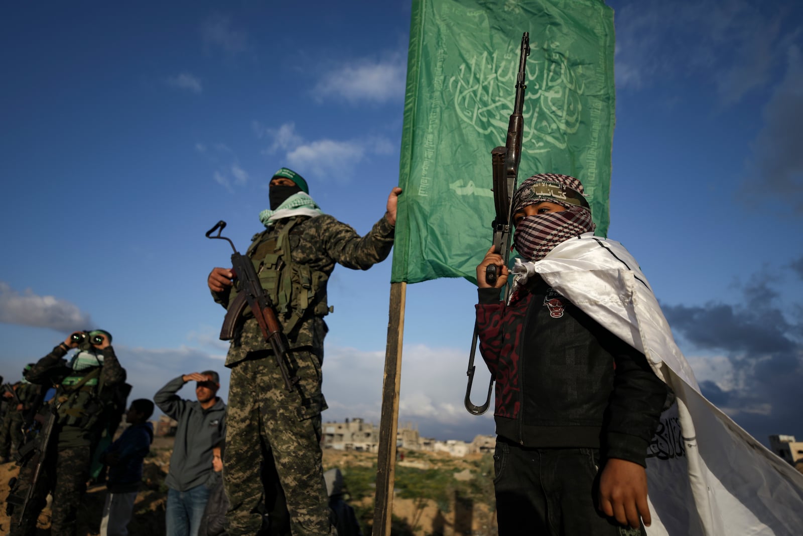 Hamas fighters take up a position ahead of handing over the bodies of four Israeli hostages, including a mother and her two children, who had long been feared dead, to the Red Cross in Khan Younis, southern Gaza Strip, Thursday, Feb. 20, 2025. (AP Photo/Jehad Alshrafi)