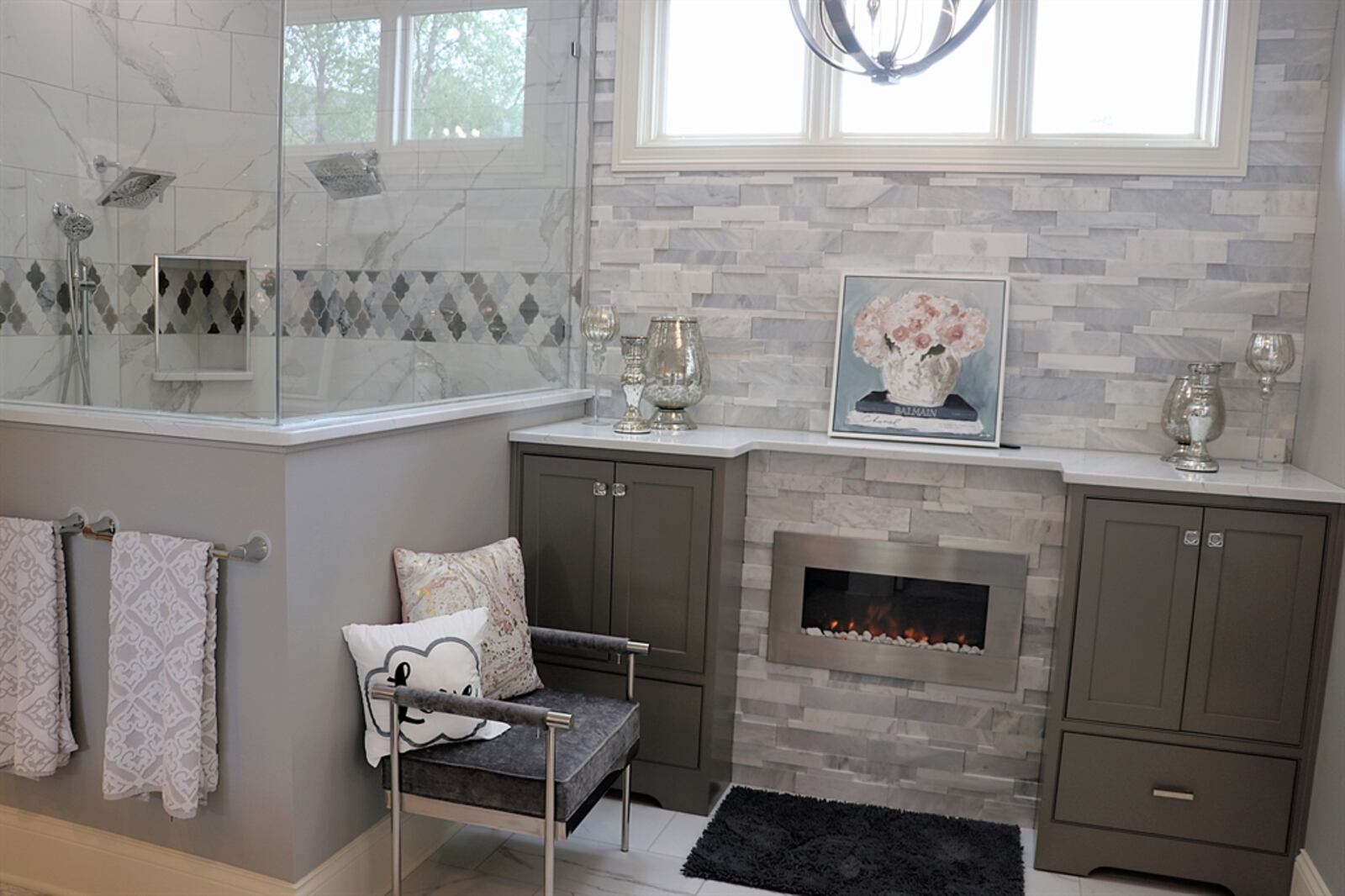 The bathroom has an electric fireplace flanked by built-in storage. The walk-in ceramic-tile shower has dual shower heads and a bench seat.