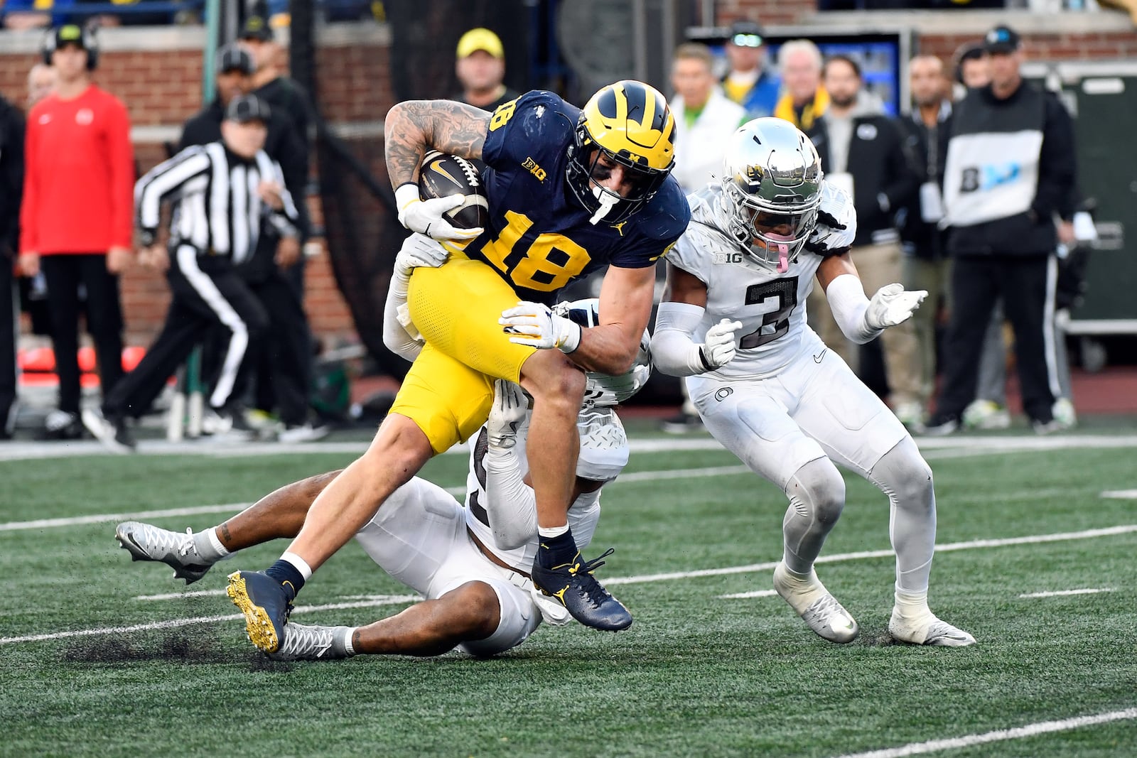 Michigan tight end Colston Loveland (18) runs after making a catch and is tackled by Oregon defensive backs Kobe Savage (5) and Brandon Johnson (3) in the second half of an NCAA college football game, Saturday, Nov. 2, 2024, in Ann Arbor, Mich. Oregon defeated Michigan 38-17. (AP Photo/Jose Juarez)