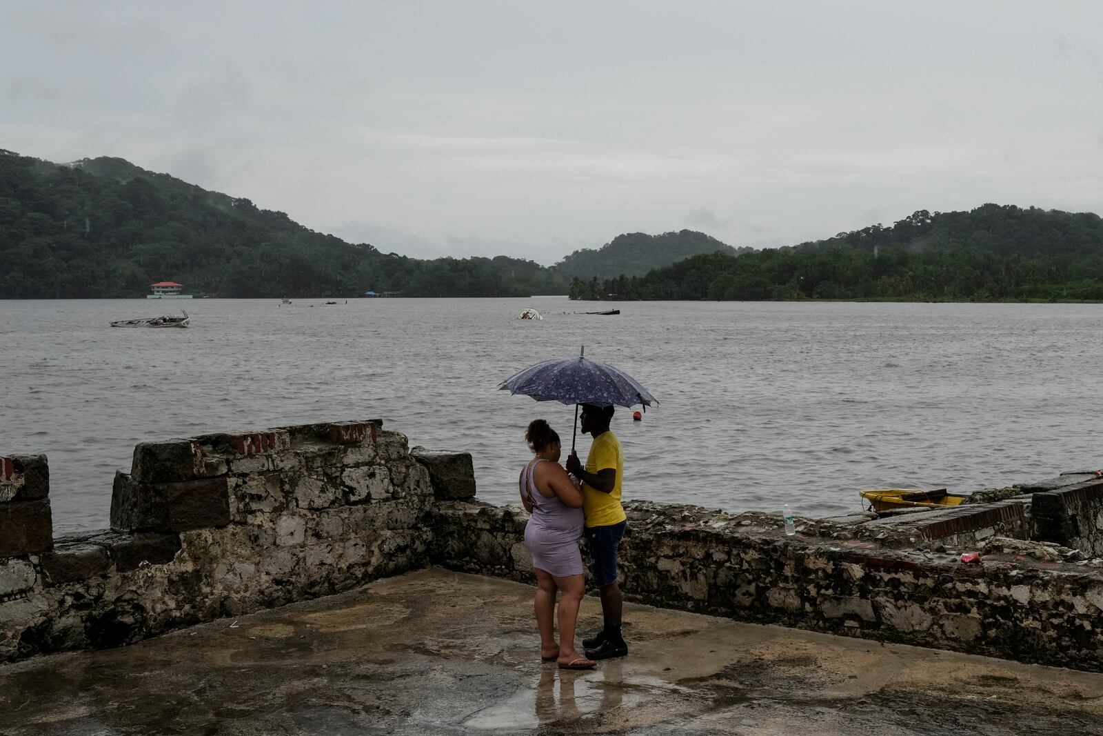 People stand under an umbrella at the San Jeronimo fort in Portobelo, Panama, Sunday, Oct. 20, 2024, a day before the Black Christ festival. (AP Photo/Matias Delacroix)