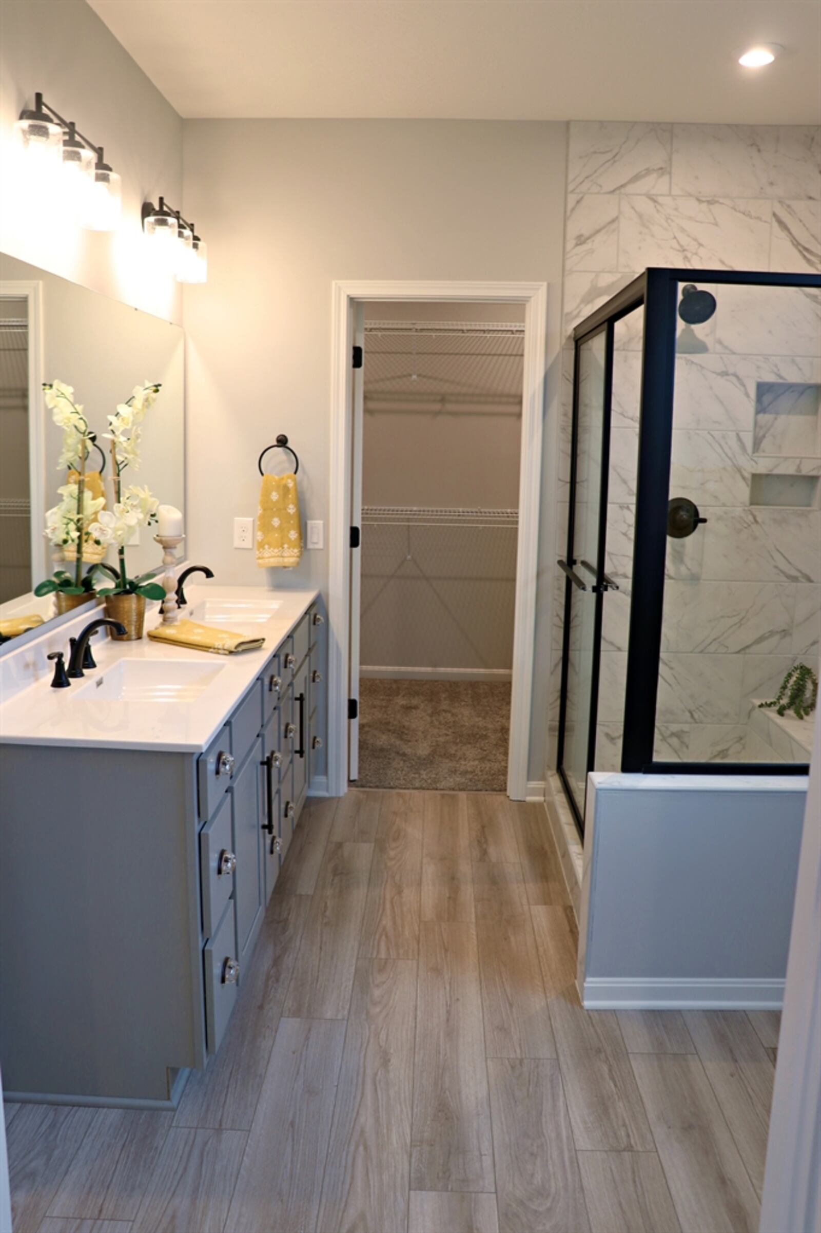 The primary bathroom has an elevated vanity with two sinks and a large walk-in shower with ceramic-tile surround. 