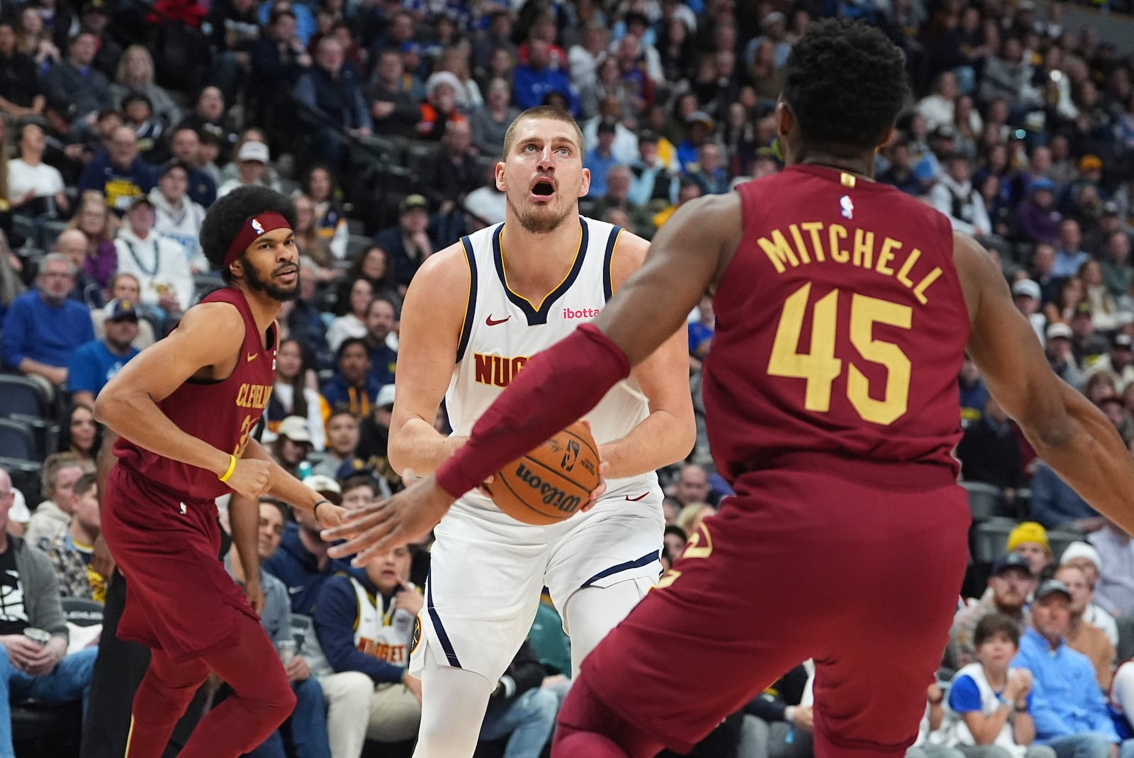 Denver Nuggets center Nikola Jokic drives between Cleveland Cavaliers center Jarrett Allen, left, and guard Donovan Mitchell, right, in the first half of an NBA basketball game Friday, Dec. 27, 2024, in Denver. (AP Photo/David Zalubowski)