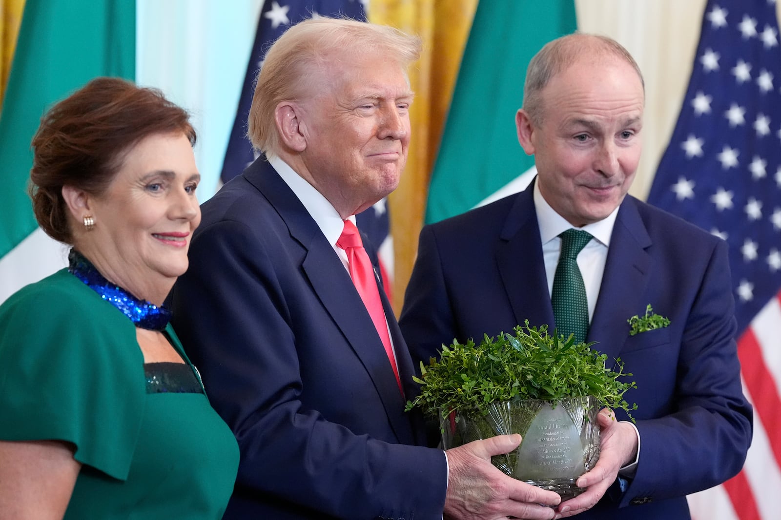 Ireland's Prime Minister Micheál Martin and his wife Mary O'Shea pose with President Donald Trump as they hold a bowl of shamrocks during an event in the East Room of the White House in Washington, Wednesday, March 12, 2025. (AP Photo/Alex Brandon)