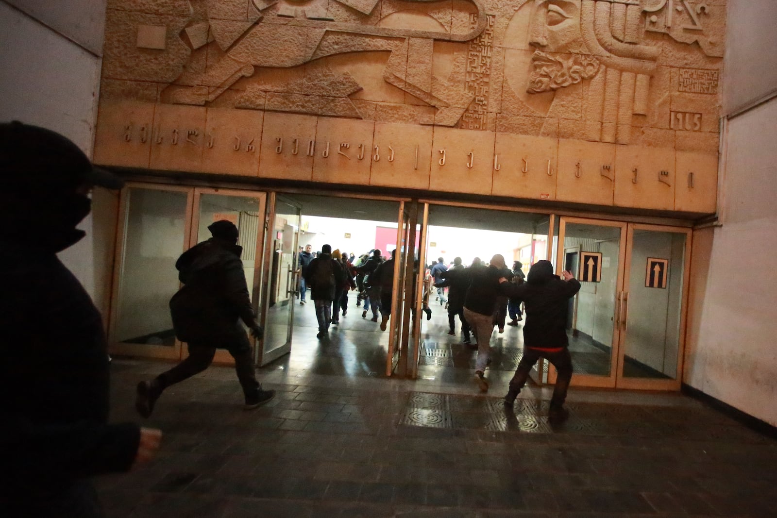 Demonstrators run to hide from the police in a subway station during a rally against the government's decision to suspend negotiations on joining the European Union for four years in Tbilisi, Georgia, Monday, Dec. 2, 2024. (AP Photo/Zurab Tsertsvadze)