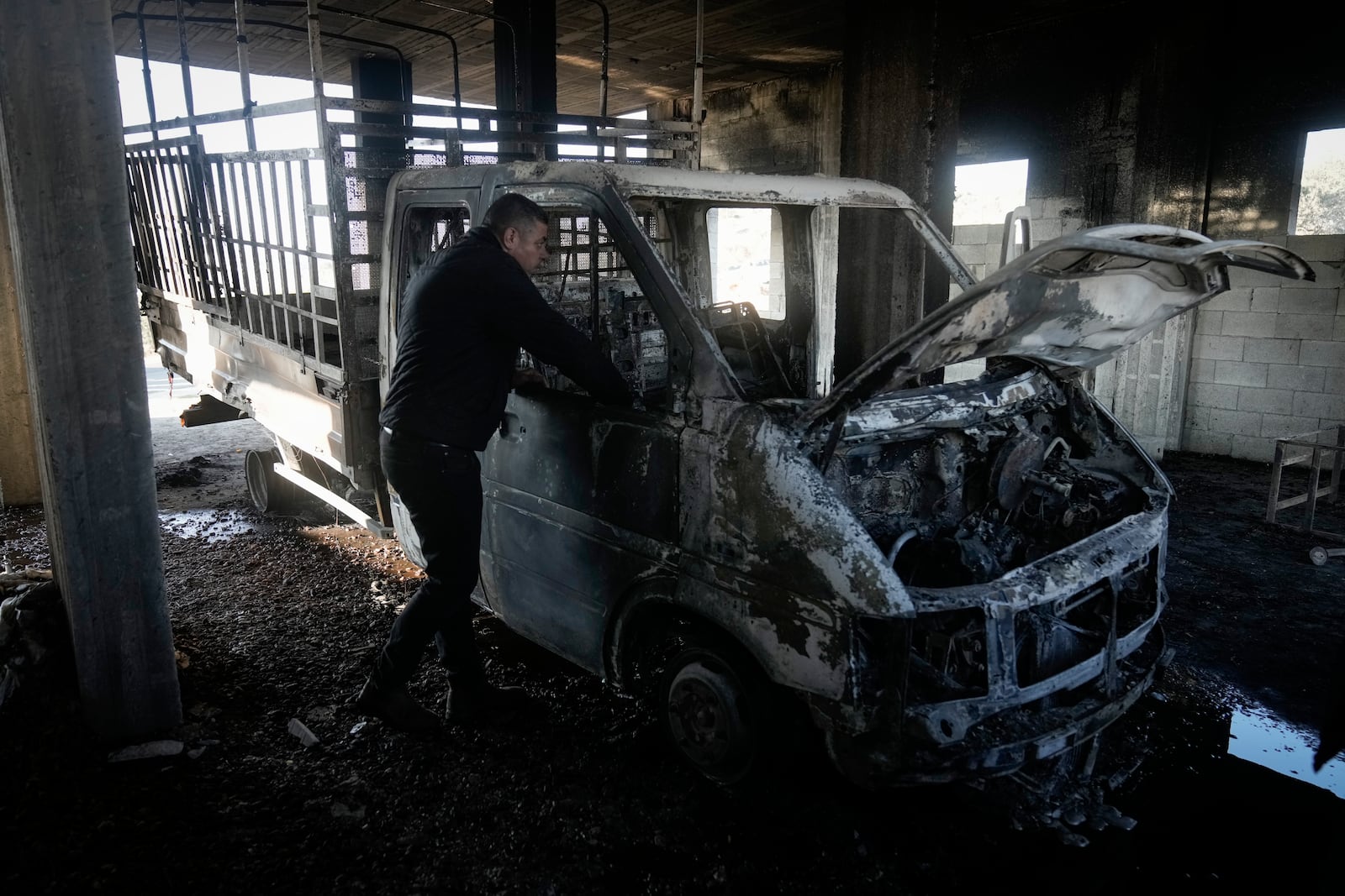 Mohammed Hanani looks at his burnt car following a settler attack that damaged vehicles and houses in the village of Beit Furik, in the occupied West Bank city of Nablus, Wednesday, Dec. 4, 2024. (AP Photo/Majdi Mohammed)