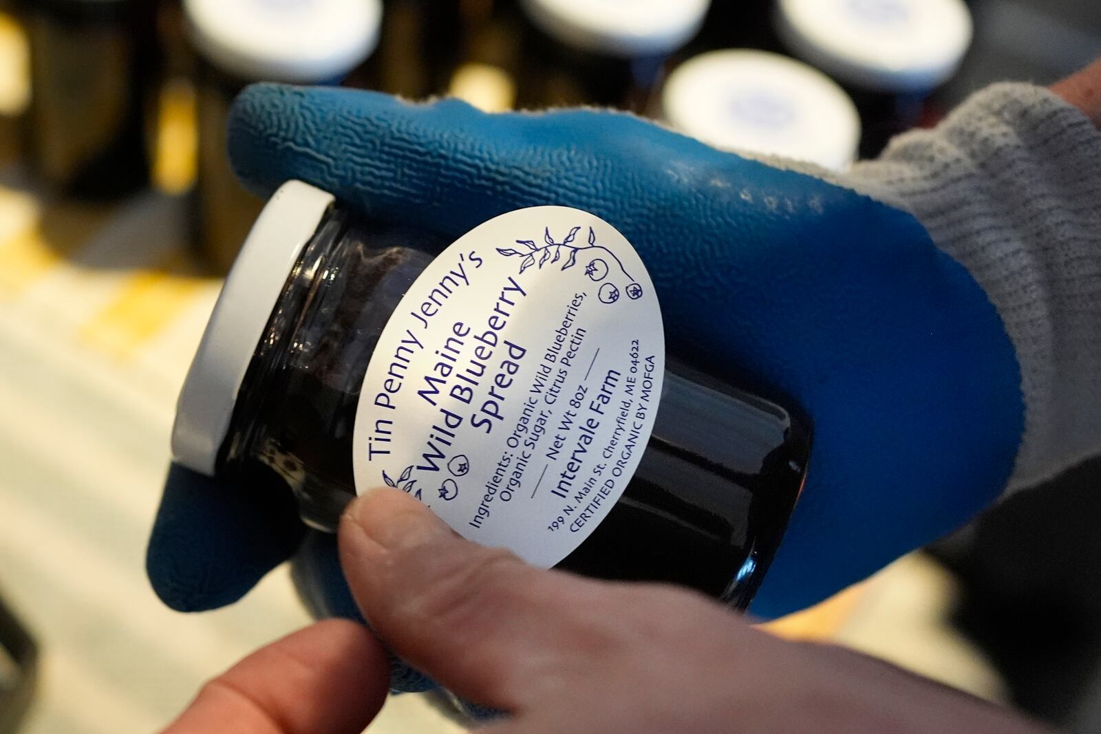 Hugh Lassen adds a label to a jar of wild blueberry spread, Monday, Feb. 10, 2025, in Cherryfield, Maine. (AP Photo/Robert F. Bukaty)