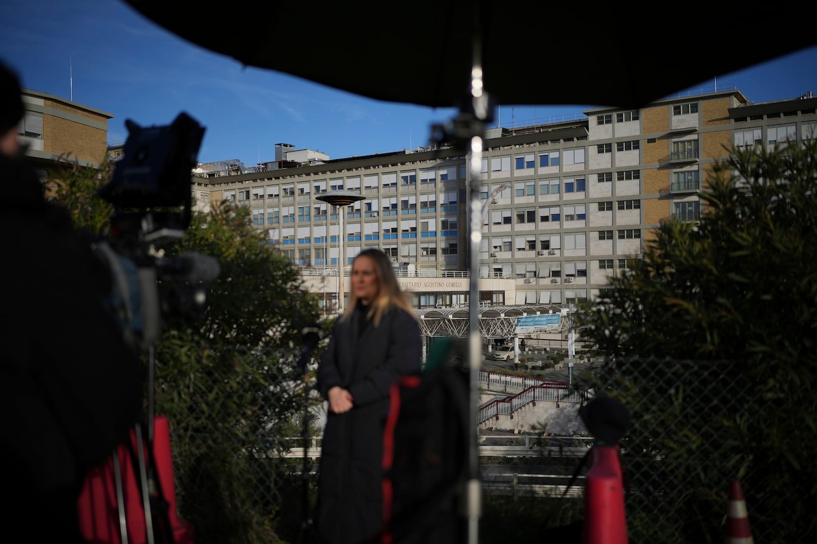 Journalists report from outside the Agostino Gemelli Polyclinic in Rome, Sunday, Feb. 16, 2025, where Pope Francis was hospitalised Friday after a week-long bout of bronchitis worsened and is receiving drug therapy for a respiratory tract infection that made impossible for him to attend the traditional Sunday noon blessing of faithful. (AP Photo/Alessandra Tarantino)