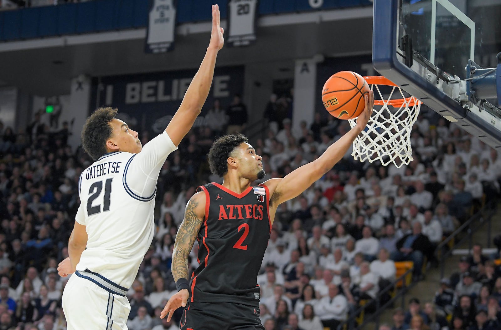 San Diego State guard Nick Boyd (2) drives to the basket as Utah State center Aubin Gateretse (21) defends in the second half of an NCAA college basketball game Saturday, Feb. 22, 2025, in Logan, Utah. (Eli Lucero/The Herald Journal via AP)