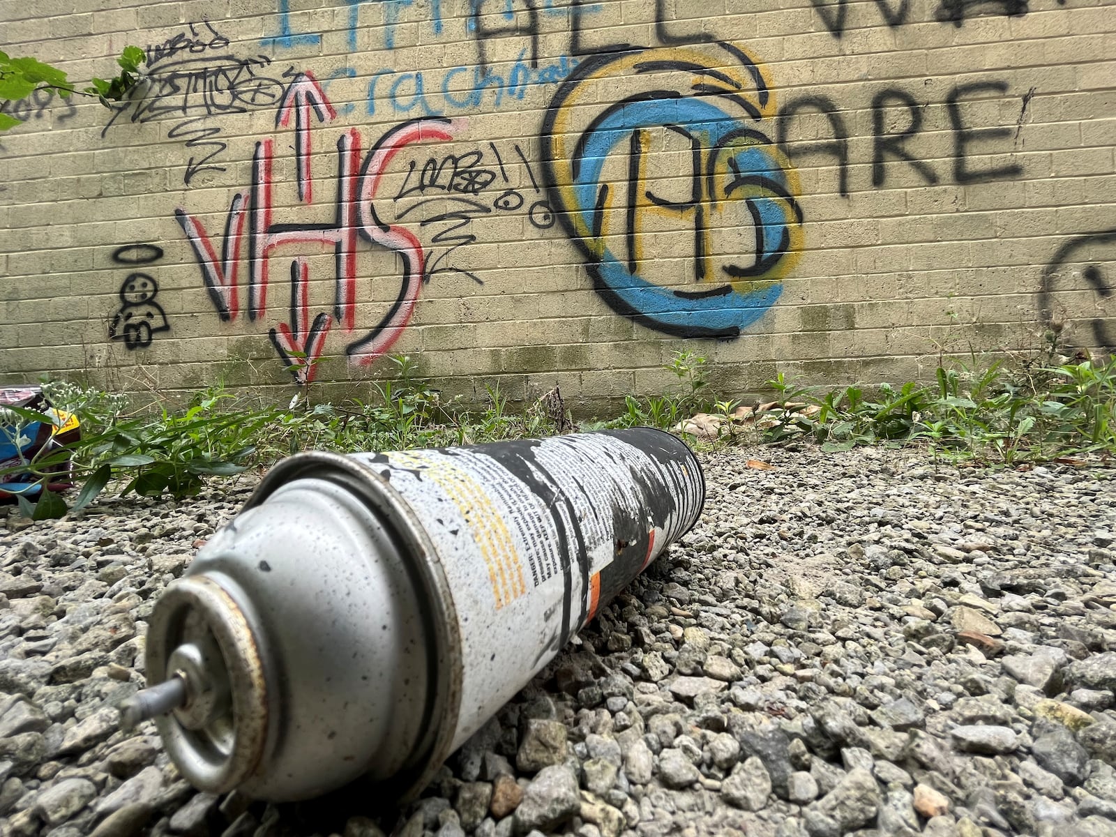 An empty spray paint bottle lies next to a wall lined with graffiti tags at a building on West First Street in downtown Dayton. CORNELIUS FROLIK / STAFF