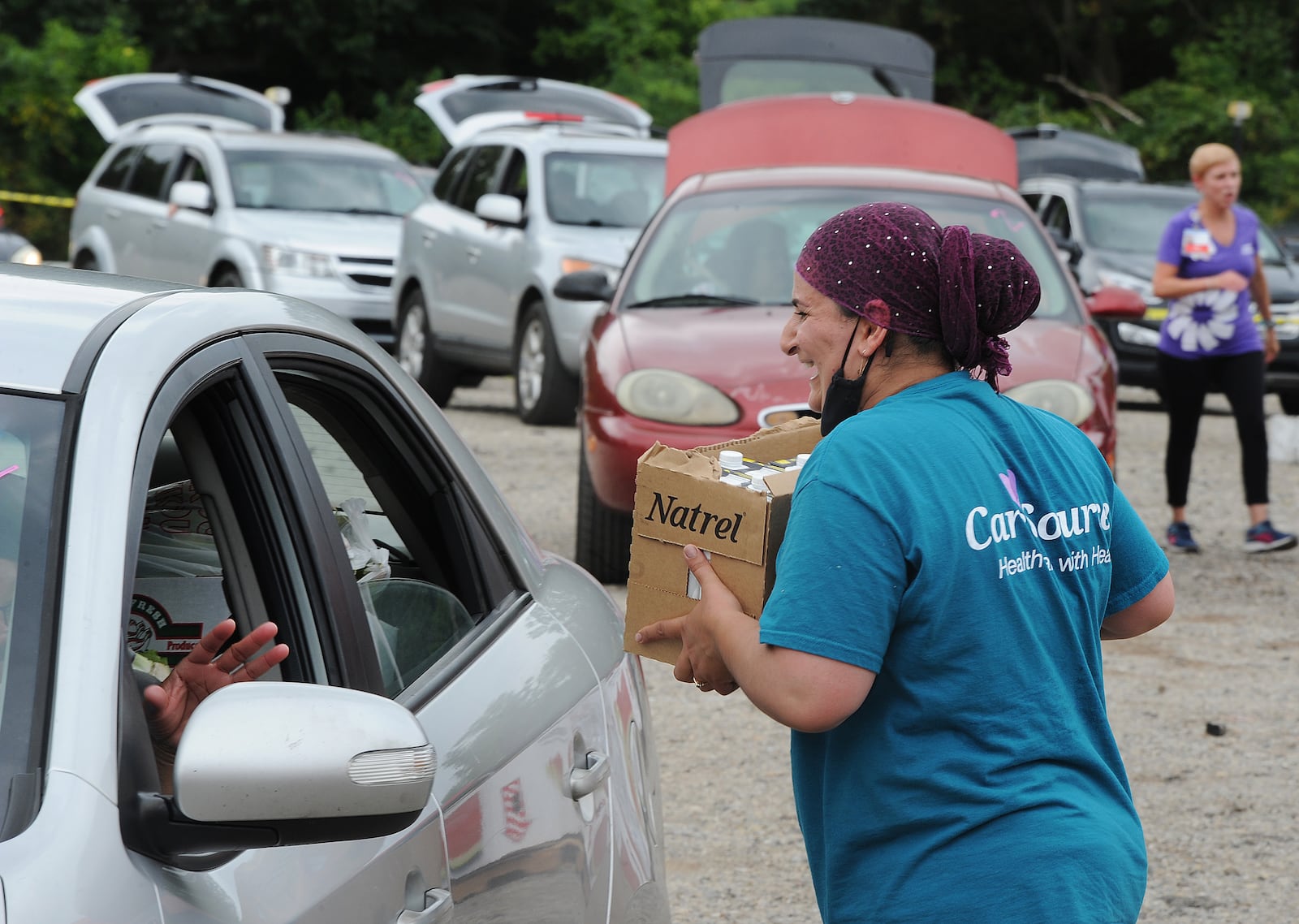 Kamilla Mamedova helps loads vehicles on Tuesday Aug. 16, 2021, during the mass drive-through food distribution at the Dixie Twin Drive-In hosted by The Foodbank. MARSHALL GORBY\STAFF