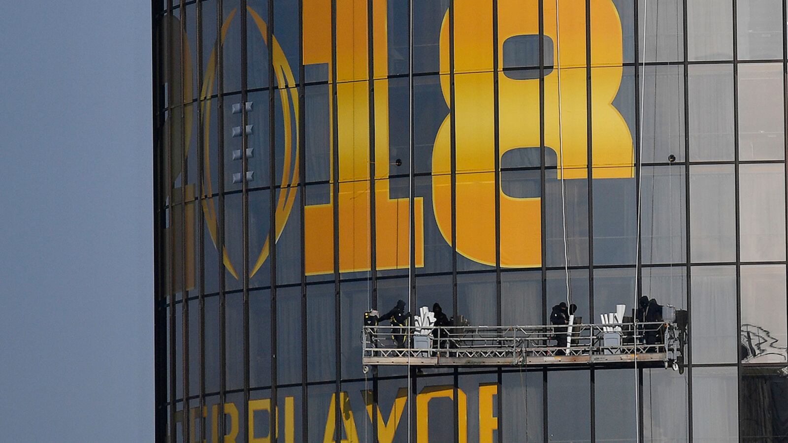 Workers place signage on a hotel announcing the NCAA national championship football game, Wednesday, Jan. 3, 2018, in Atlanta. Alabama and Georgia won their College Football Playoff semifinals on Monday and will meet in the national championship next week in Atlanta. (AP Photo/Mike Stewart)