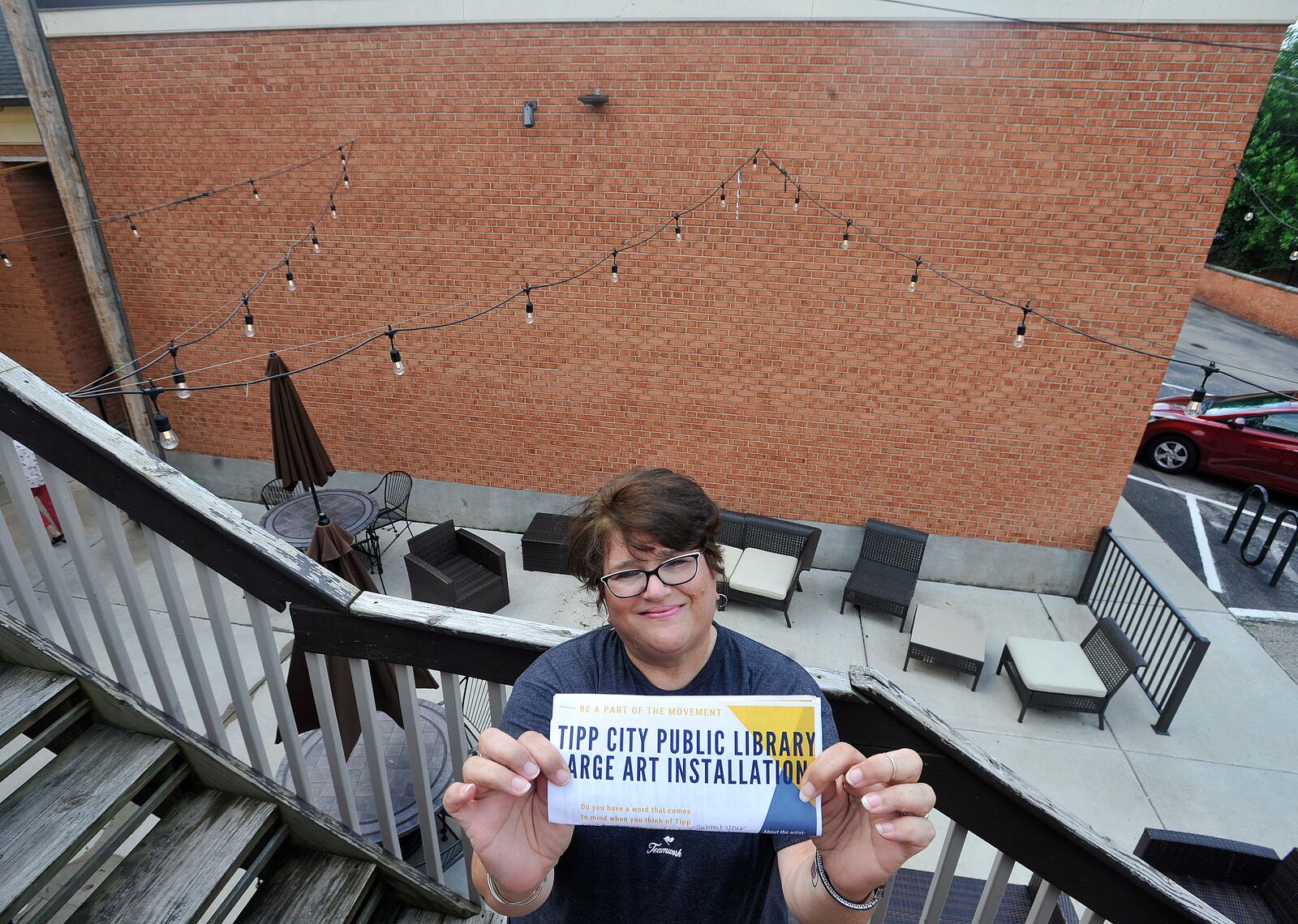 Lisa Santucci, director of the Tipp City Public Library, stands in front of the wall where a proposed mural will be done by an artist who is a Tipp City graduate. The site is downtown Tipp City, between the library and Coldwate Café. MARSHALL GORBY/STAFF