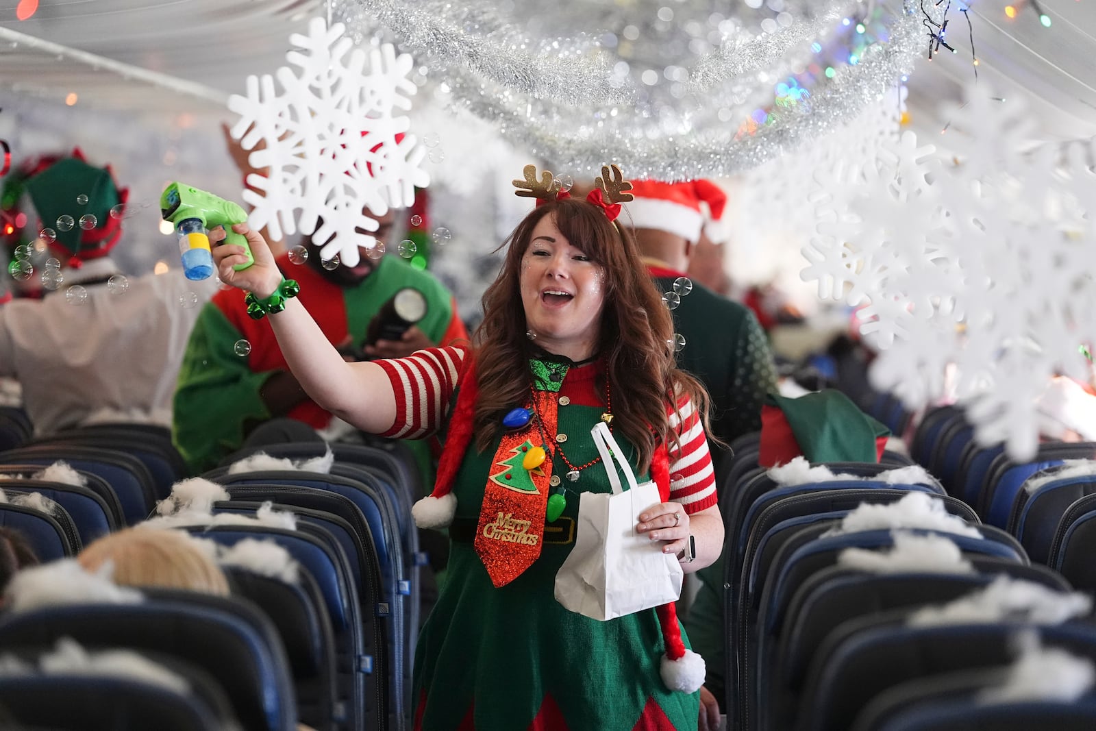 A flight attendant sprays bubbles during the United Airlines annual "fantasy flight" to a fictional North Pole at Denver International Airport, Saturday, Dec. 14, 2024, in Denver. (AP Photo/David Zalubowski)