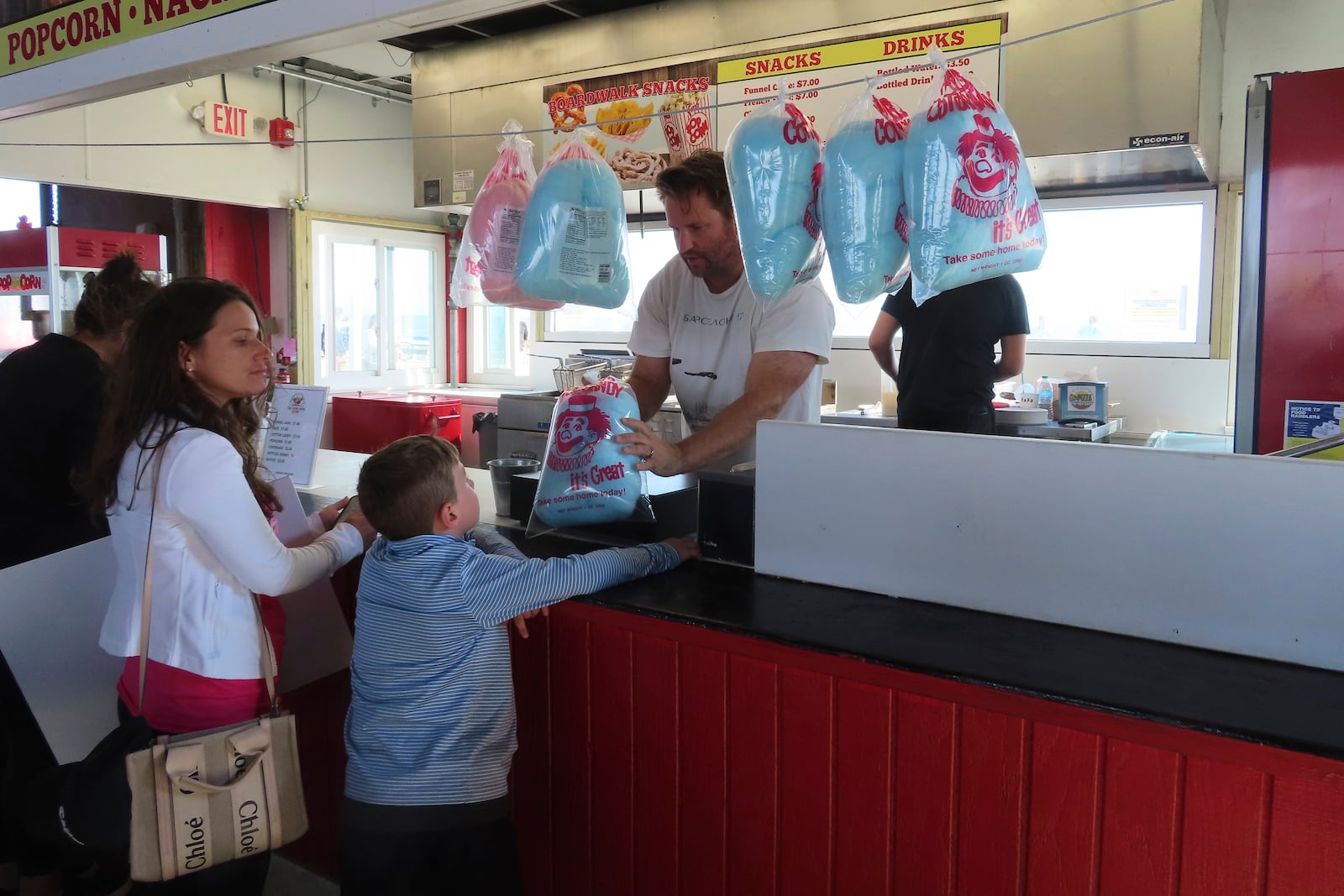 A worker at Gillian's Wonderland, the popular amusement park on the boardwalk in Ocean City, N.J., hands a bag of cotton candy to a child during the park's final day of operation before shutting down for good, Sunday, Oct. 13, 2024. (AP Photo/Wayne Parry)