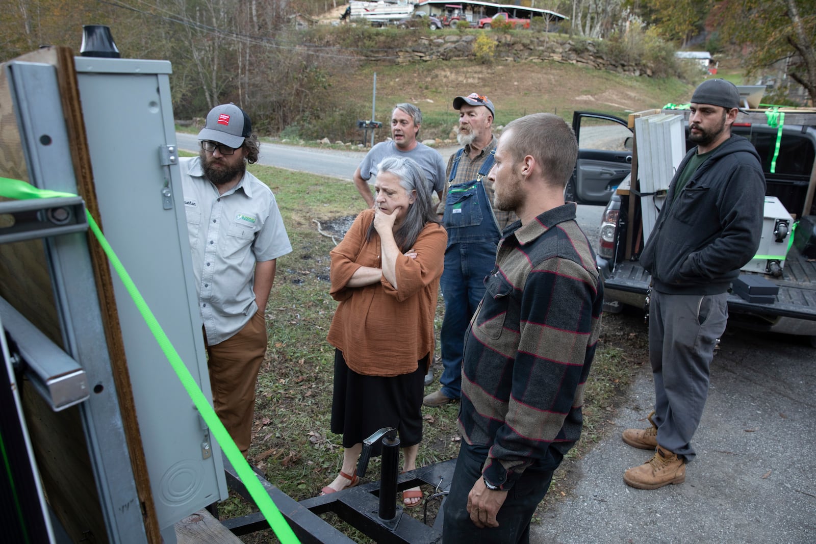 Jonathan Bowen, far left, shows Pam Phillips, center, how to use a mobile power unit that will now help power the resource hub she operates in Bakersville, N.C. on Oct. 9, 2024. (AP Photo/Gabriela Aoun Angueria)