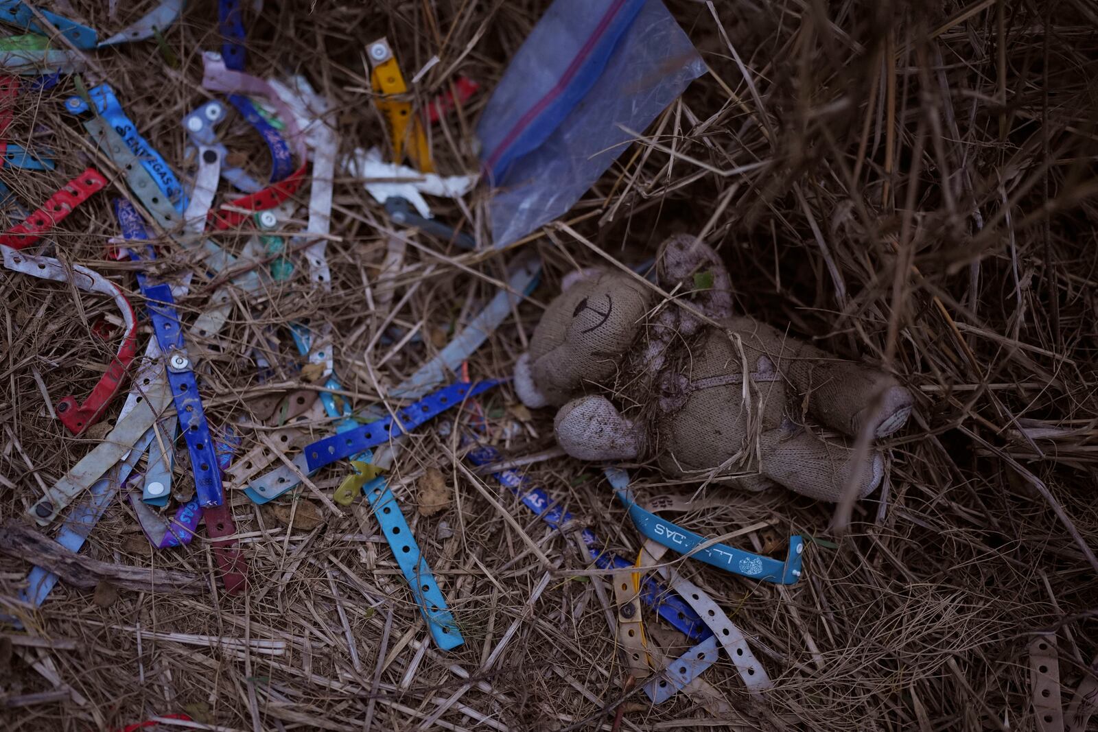 A teddy bear and bracelets used by human smuggling groups litter a trail near the Rio Grande at the U.S.-Mexico border, Thursday, Feb. 13, 2025, in McAllen, Texas. (AP Photo/Eric Gay)