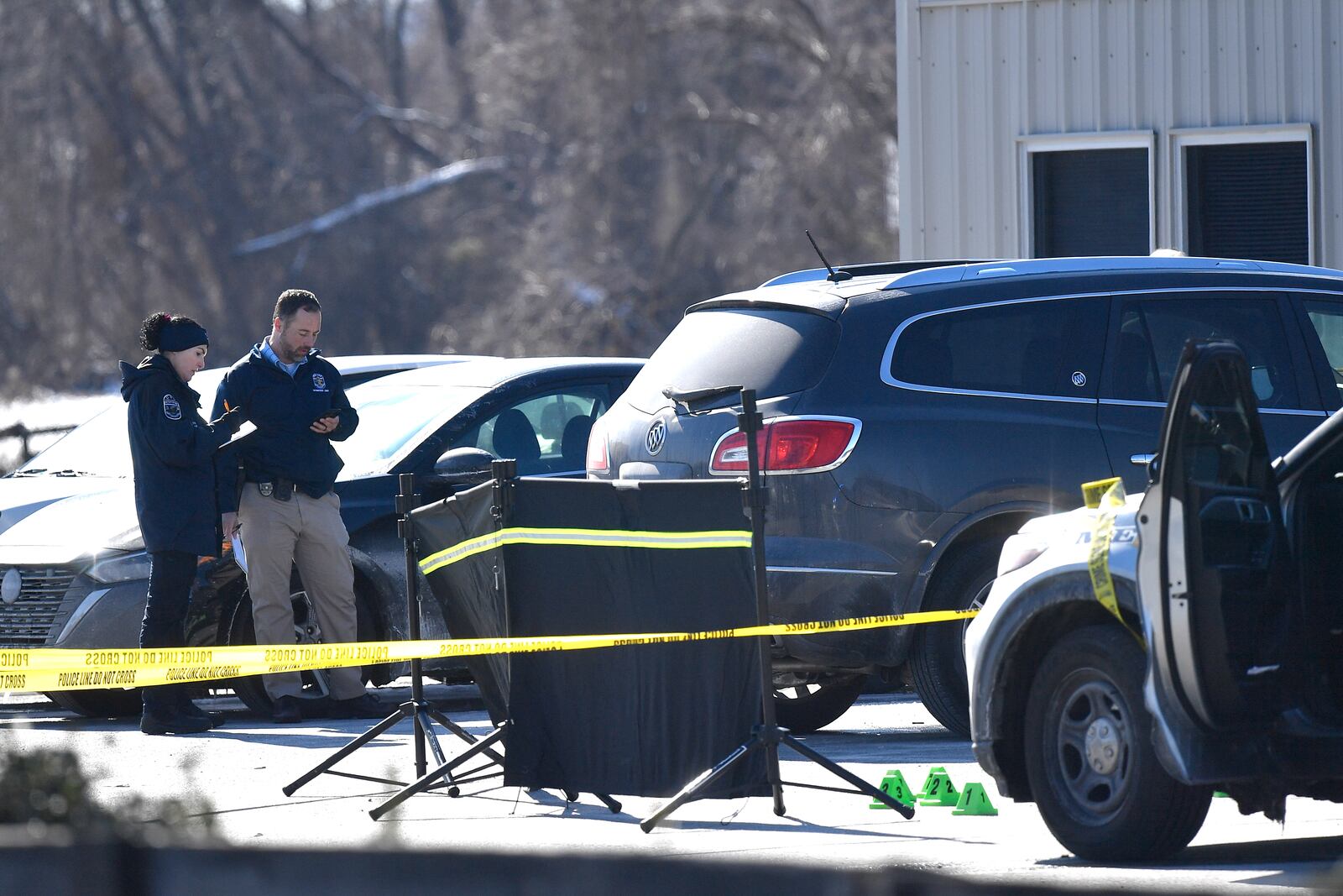 Detectives with the Louisville Metro Crime Scene unit examines a scene of a deadly shooting outside a motor vehicle office in Louisville, Ky., Friday, Feb. 21, 2025. (AP Photo/Timothy D. Easley)