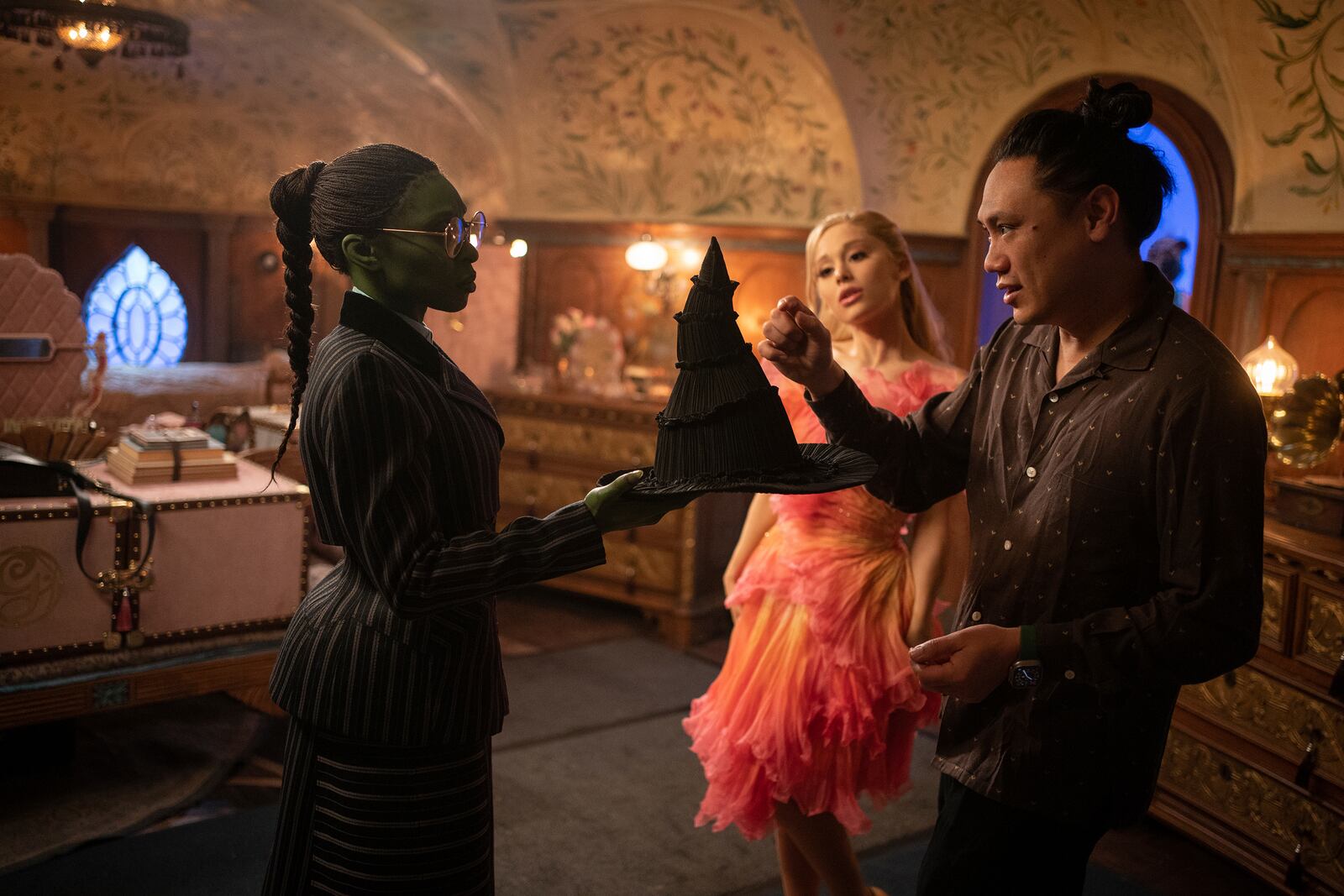 This image released by Universal Pictures shows Cynthia Erivo, left, and Ariana Grande, with director Jon M. Chu, right, on the set of the film "Wicked." (Universal Pictures via AP)