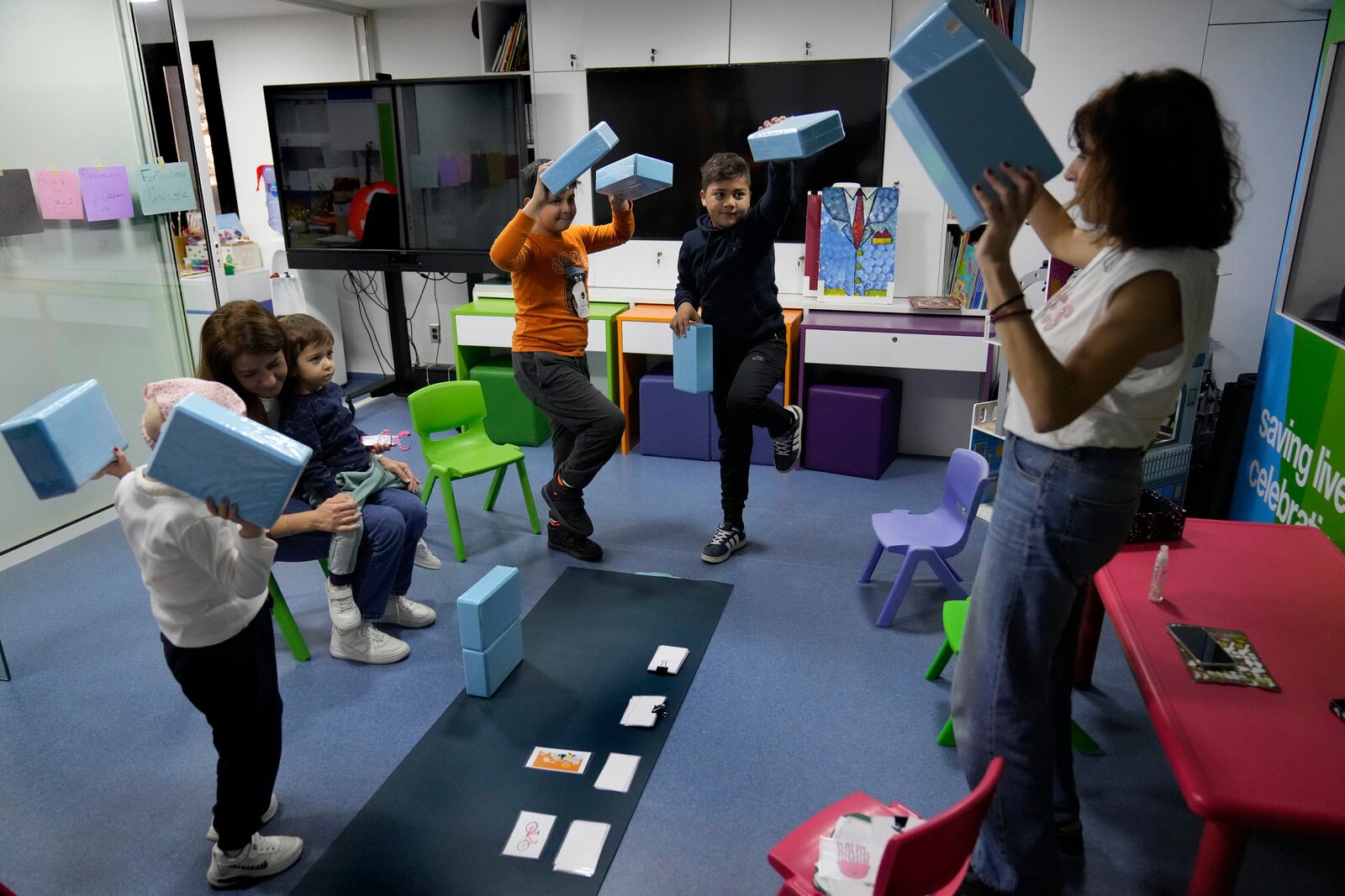 Children who suffers from cancer, enjoy at a playroom with a volunteer ahead of their treatments at the Children's Cancer Center of Lebanon, in Beirut, Lebanon, Friday, Nov. 15, 2024. (AP Photo/Hussein Malla)