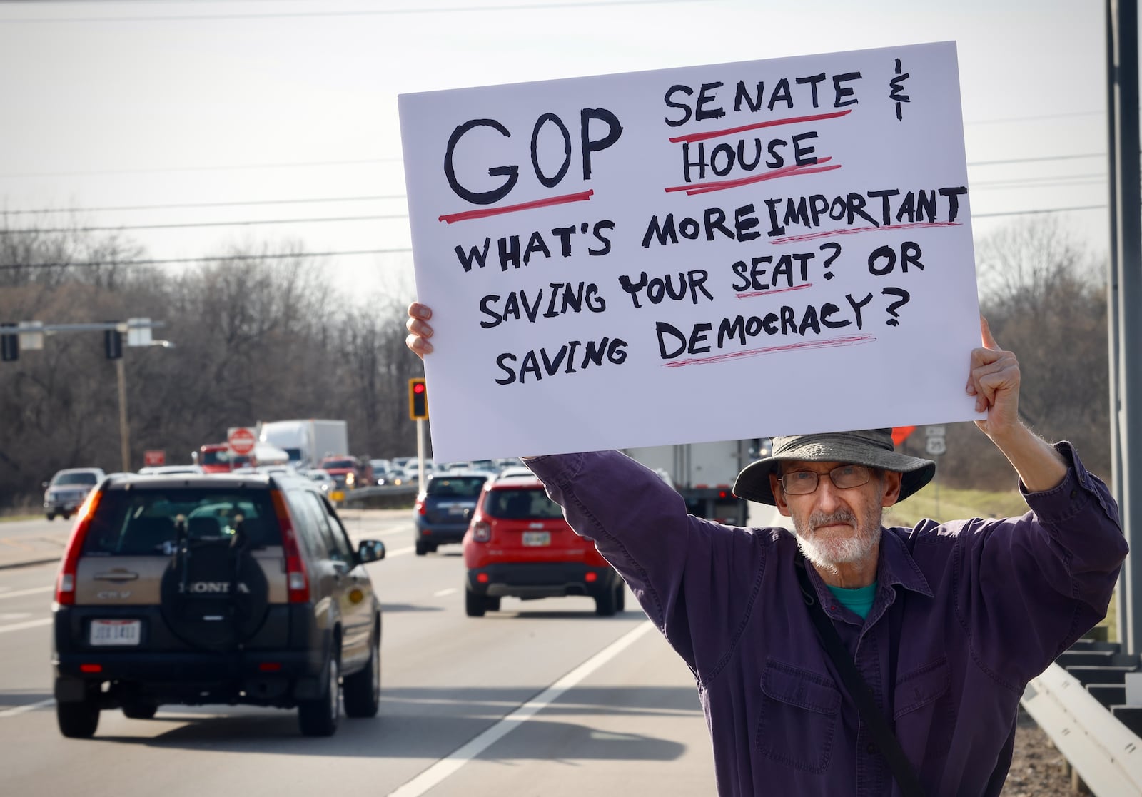 Resident Casey Kelliher holds a sign along U.S. 35 calling Republican members of Congress to action during a protest against the actions of DOGE in Beavercreek, March 18, 2025. MARSHALL GORBY/STAFF