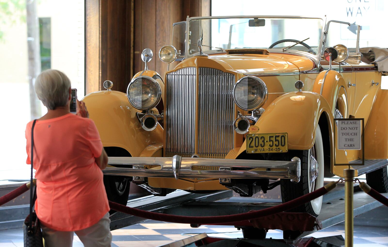 A visitor photographs a 1934 Super Eight Sport Phaeton revolving in the showroom at America’s Packard Museum, the world’s only restored Packard dealership operating as a museum. LISA POWELL / STAFF