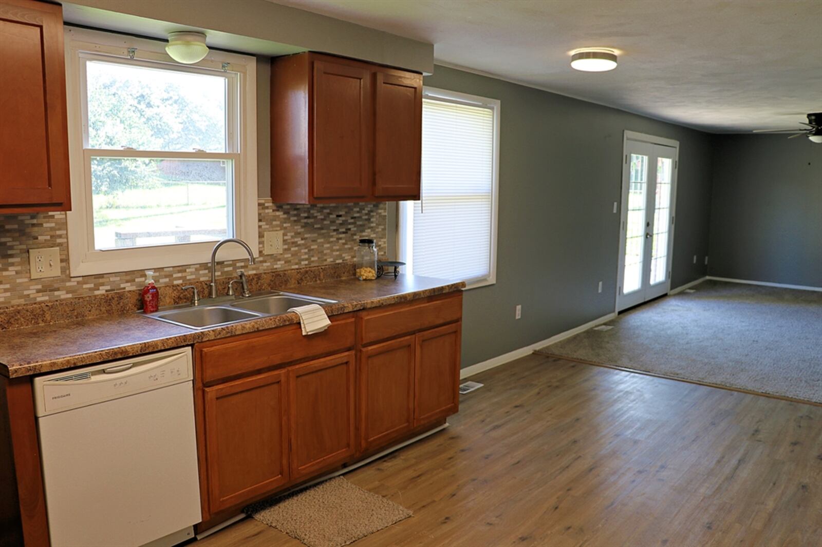 In the kitchen, mosaic glass tiles create a backsplash between the counters and maple cabinetry. 