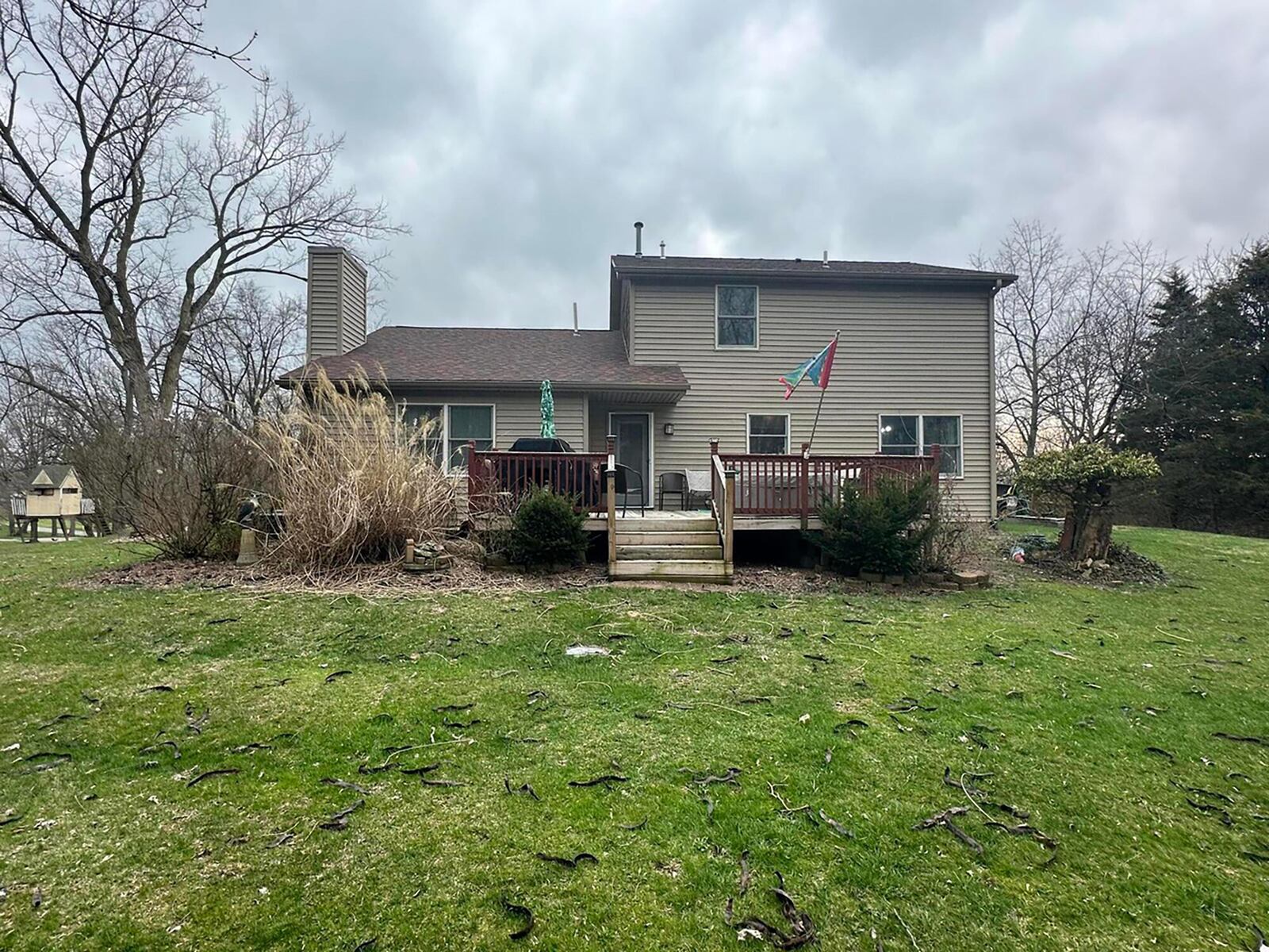 The rear of the home has a wood deck with railings and two storage sheds as well as a wood gazebo.