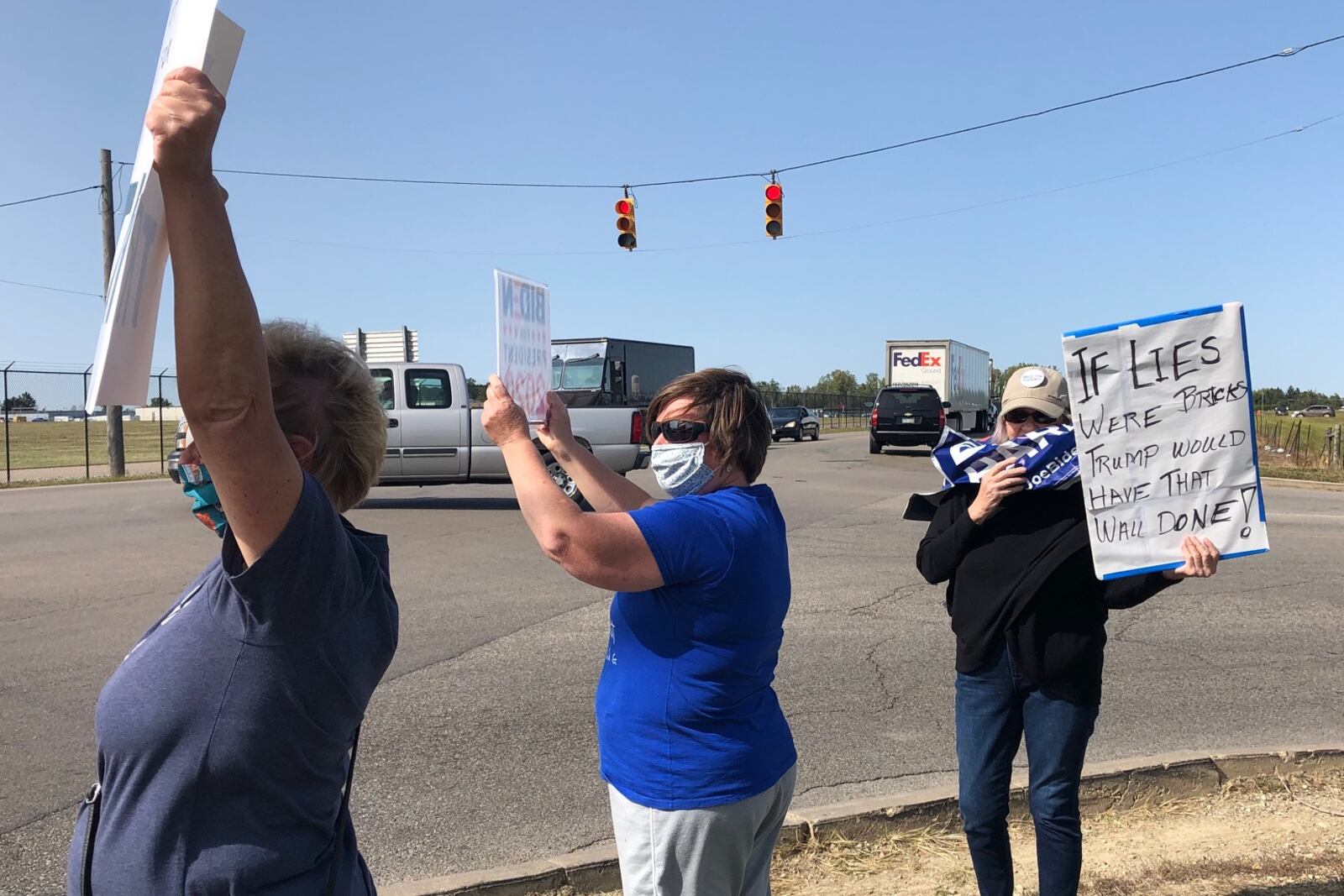 Protesters stand outside the Dayton International Airport on Monday before a visit by President Trump.