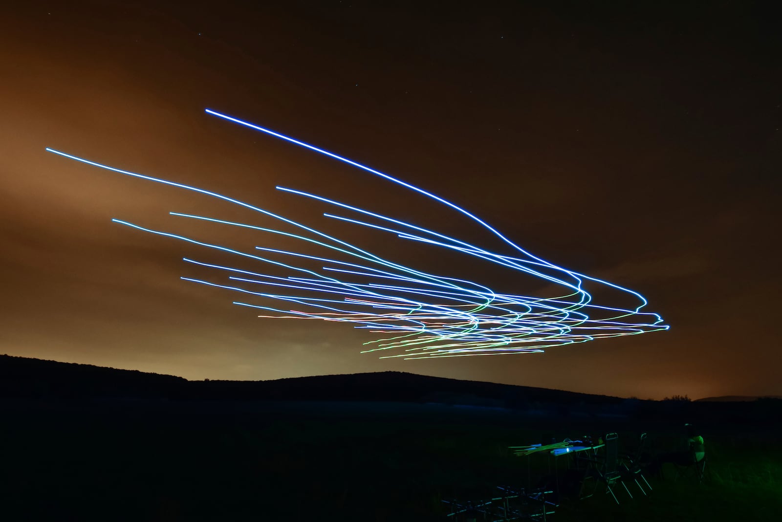 This handout photo taken with long exposure shows a researcher of the Eötvös Loránd University observing the flight of a flock of autonomous drones during an experiment near Budapest, Hungary, Thursday, Oct. 21, 2021. (AP Photo/HO/Eotvos Lorand University)