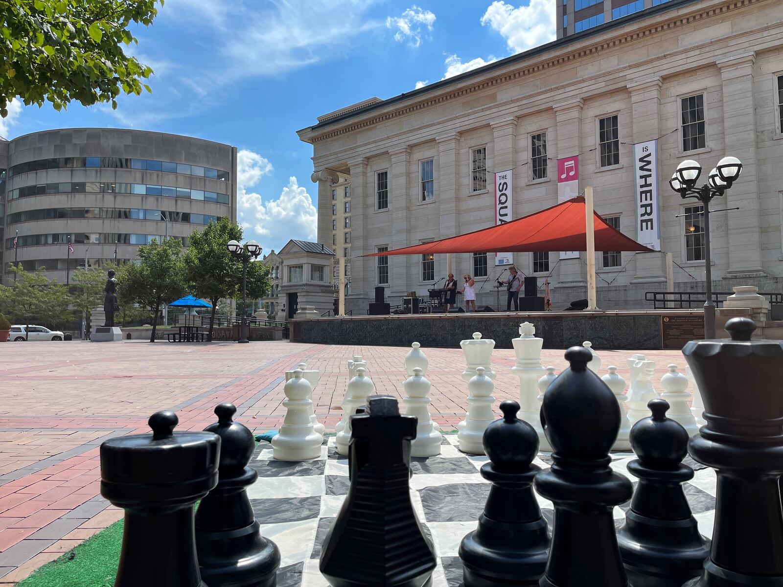 A band performs at lunchtime on Friday on the stage at Courthouse Square as part of the "Square is Where" program. An oversized chess board is one of the games people can play. CORNELIUS FROLIK / STAFF