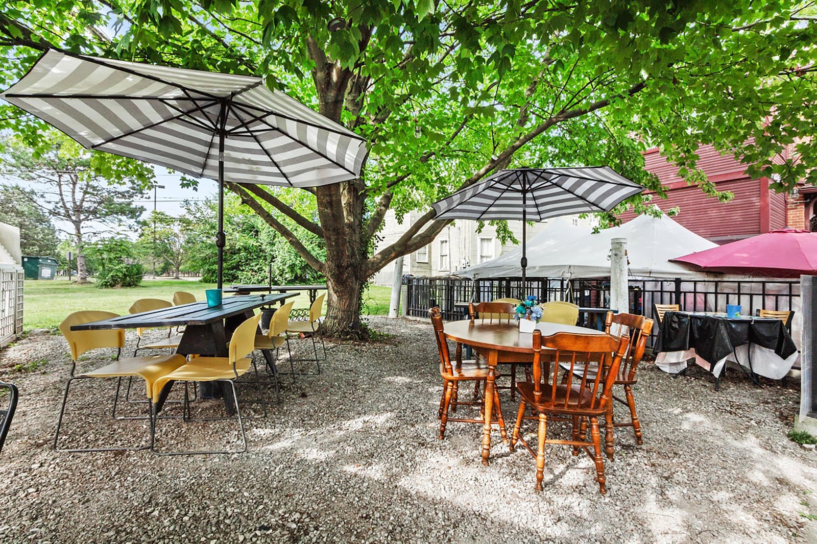 The outdoor seating area is under mature trees.