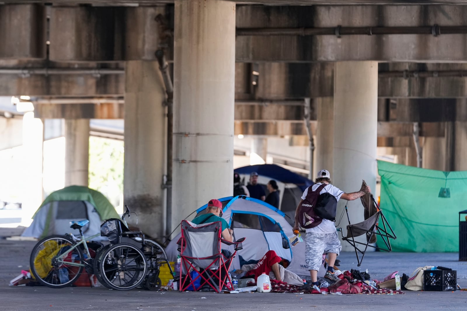 People living in a homeless encampment pick up belongings after Louisiana State police gave instructions for them to move to a different pre-designated location as they perform a sweep in advance of a Taylor Swift concert in New Orleans, Wednesday, Oct. 23, 2024. (AP Photo/Gerald Herbert)