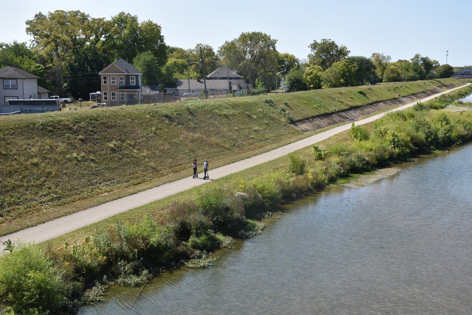 Two people on scooters ride along the Wolf Creek Trail on the southside of the Wolf Creek tributary. The city of Dayton wants to redesign sections of the flood protection levees on either side of Wolf Creek to create new ways to access the waterway. CORNELIUS FROLIK / STAFF