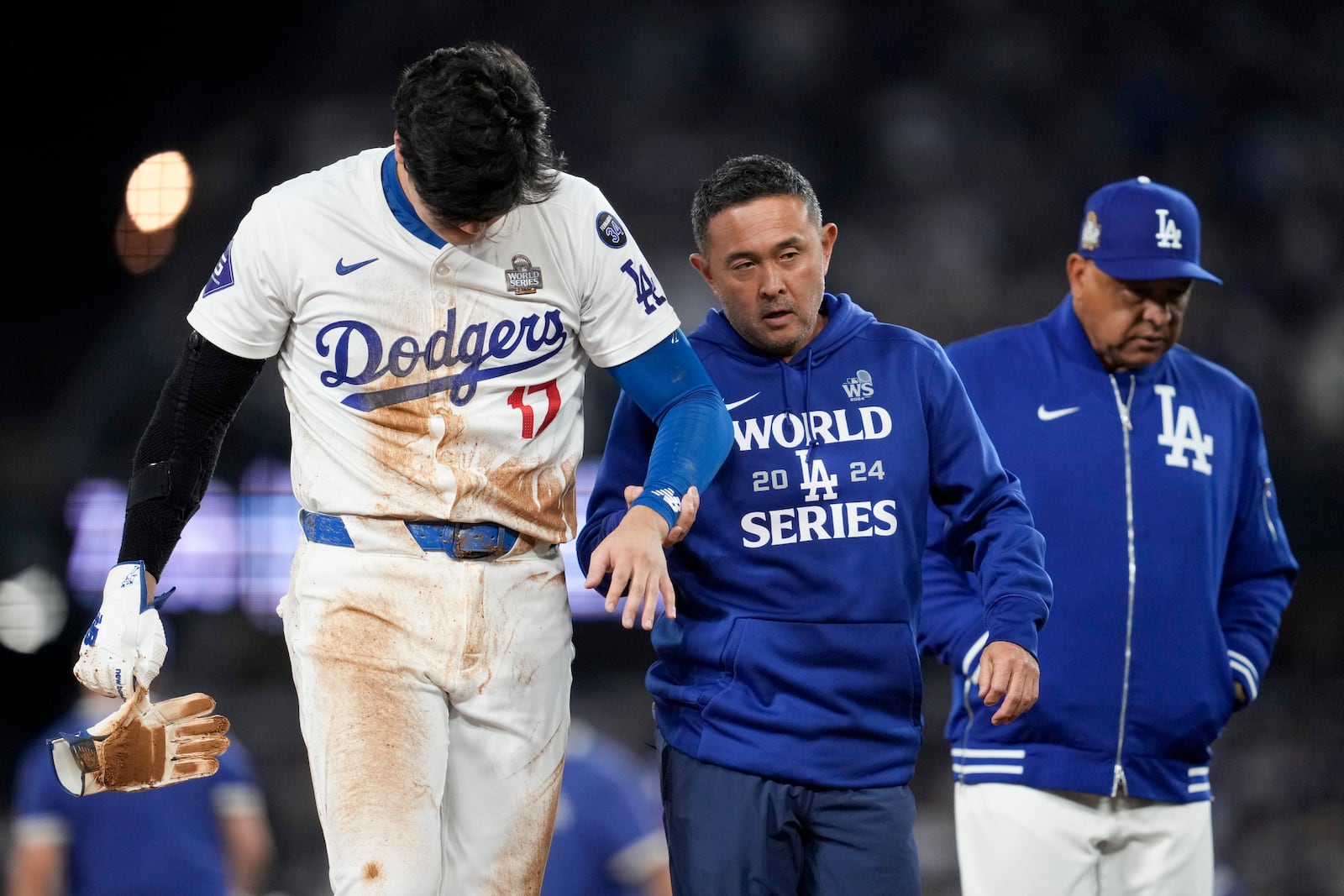 Los Angeles Dodgers' Shohei Ohtani is helped off the field after getting hurt during the seventh inning in Game 2 of the baseball World Series against the New York Yankees, Saturday, Oct. 26, 2024, in Los Angeles. (AP Photo/Ashley Landis)