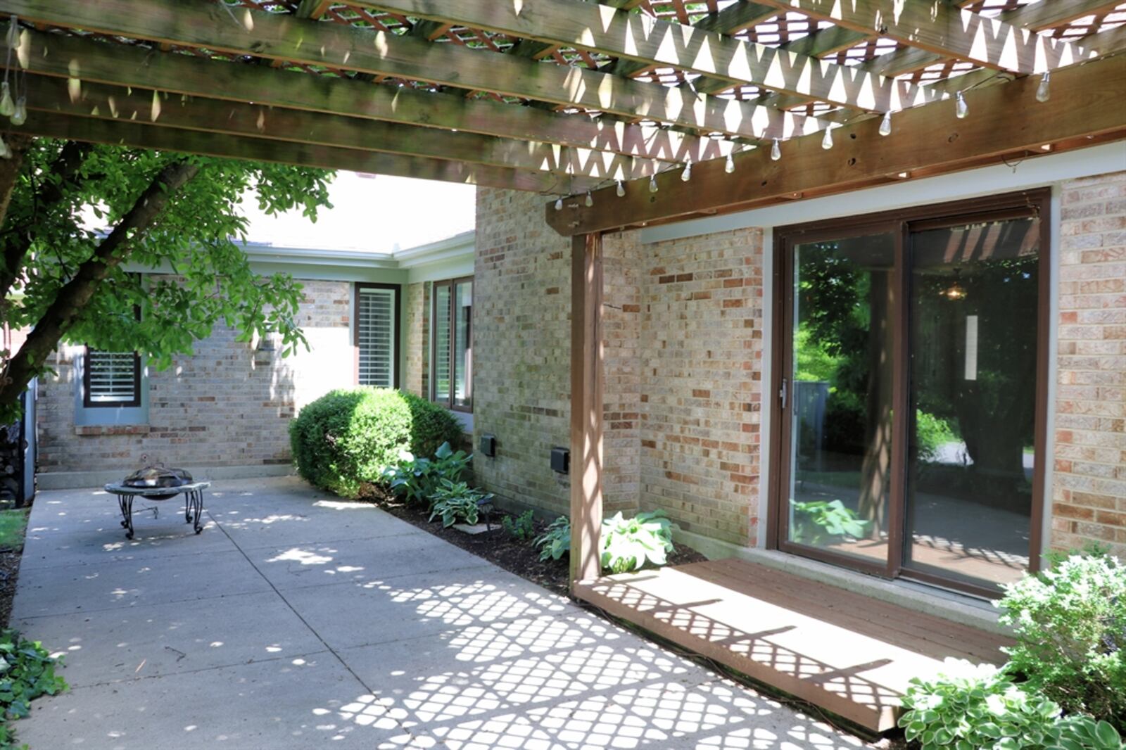 Mature landscaping wraps around a large patio and pergola for added privacy.