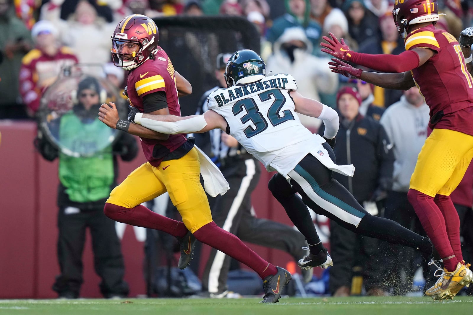 Washington Commanders quarterback Jayden Daniels (5) avoids a tackle by Philadelphia Eagles safety Reed Blankenship (32) during the second half of an NFL football game, Sunday, Dec. 22, 2024, in Landover, Md. (AP Photo/Stephanie Scarbrough)