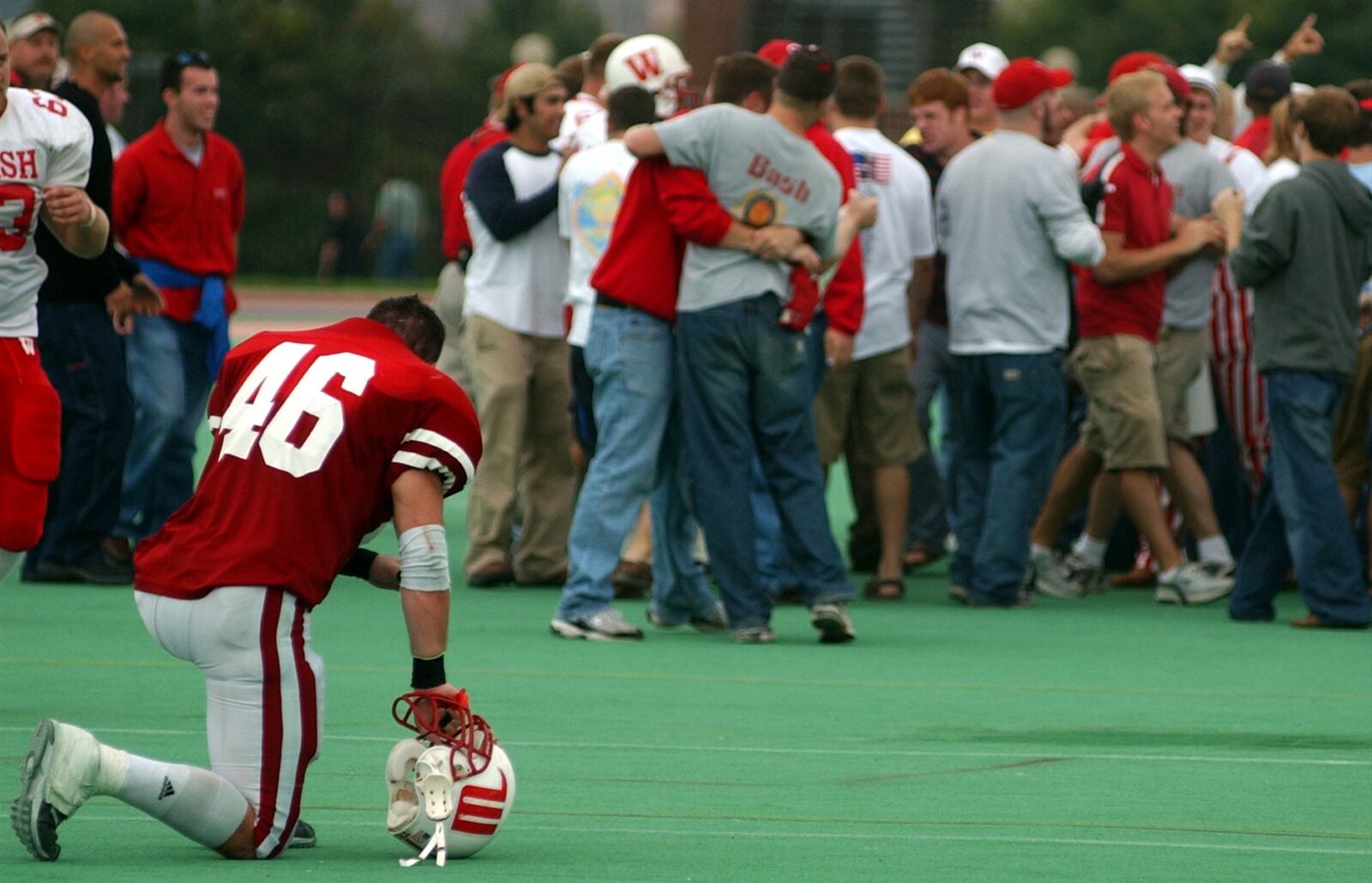 Wittenberg’s Allen D’Andrea rest on one knee in the foreground as Wabash players and fans celebrate in the background after defeating Wittenberg 46-43 in overtime on October 12, 2002. News-Sun/Bill Lackey