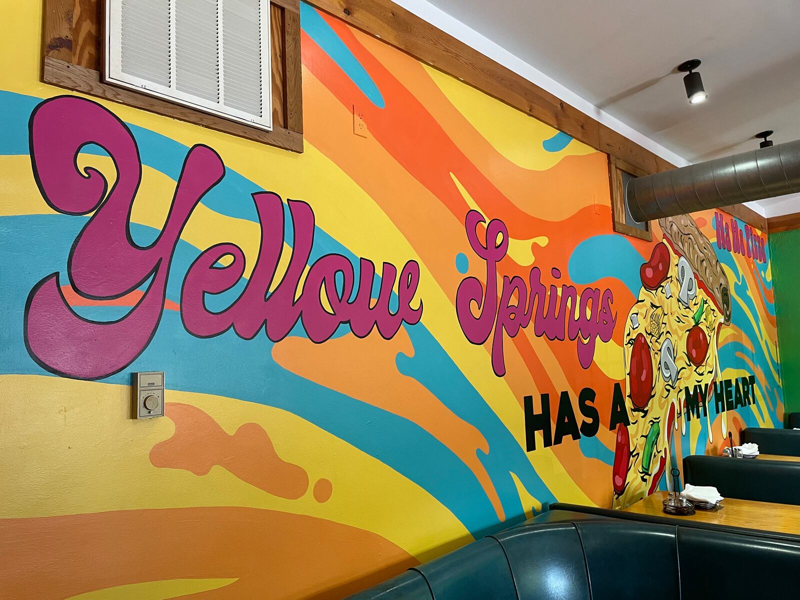 Dayton-area artist Chloé Chicarelli has put her love for Yellow Springs and Ha Ha Pizza on display through a new mural inside the pizza shop. NATALIE JONES/STAFF