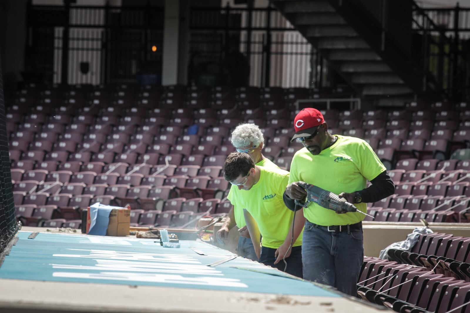 Dragon field crews from left, Emmett Wagner, Brian Greene and Britt Caudill replace the logo on the dugout at Day Air Field Wednesday May 5, 2021.