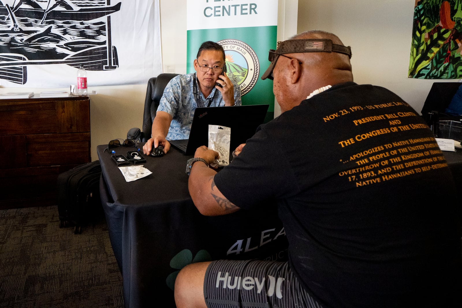 Peter Lim, a supervising building inspector for 4LEAF, helps Edyngton Naki with his permit notice, at Lahaina Resource Center, Thursday, Dec. 12, 2024, in Lahaina, Hawaii. (AP Photo/Mengshin Lin)