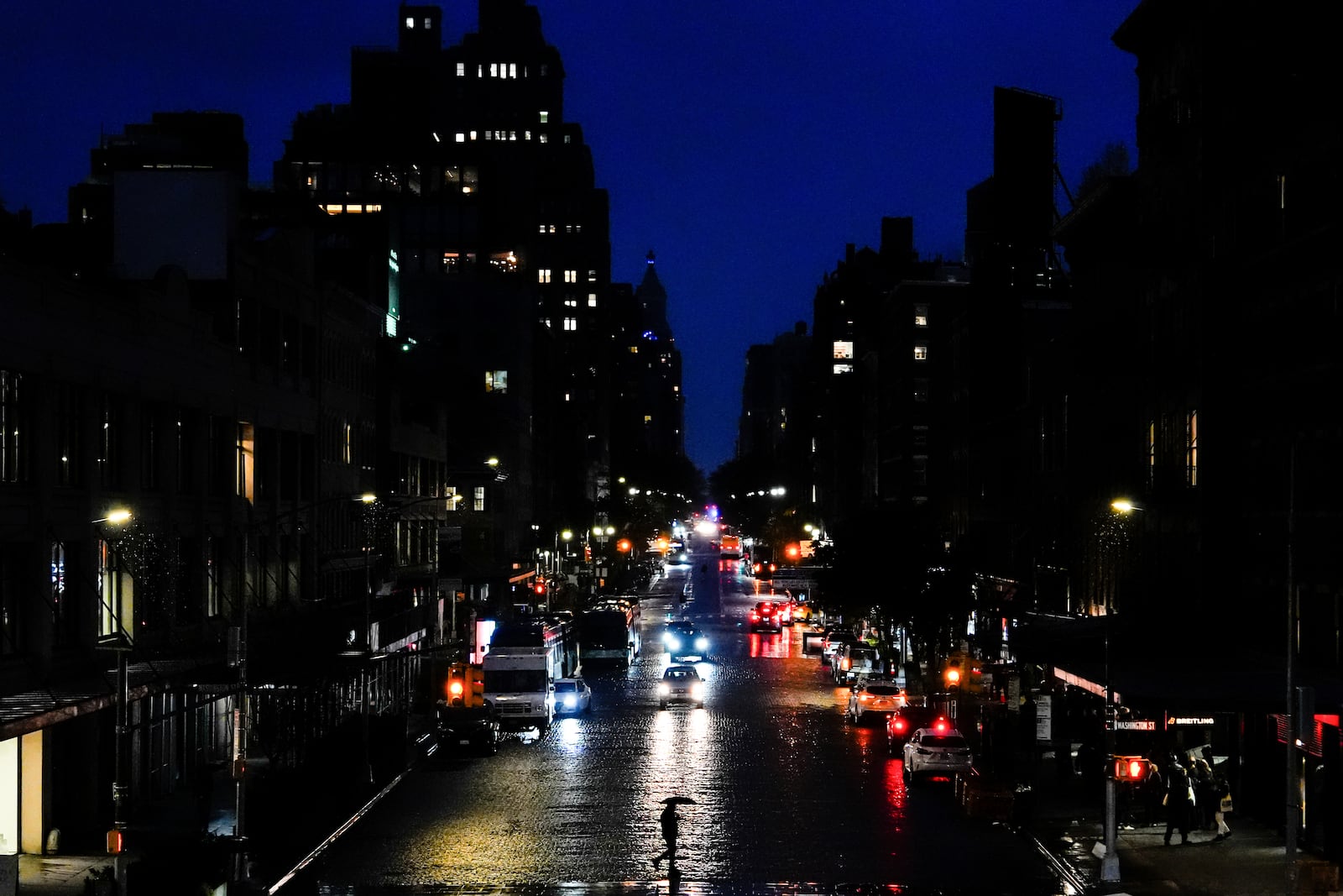 A person uses an umbrella while crossing a street in the Meatpacking District neighborhood of Manhattan, Friday, Nov. 22, 2024, in New York. (AP Photo/Julia Demaree Nikhinson)