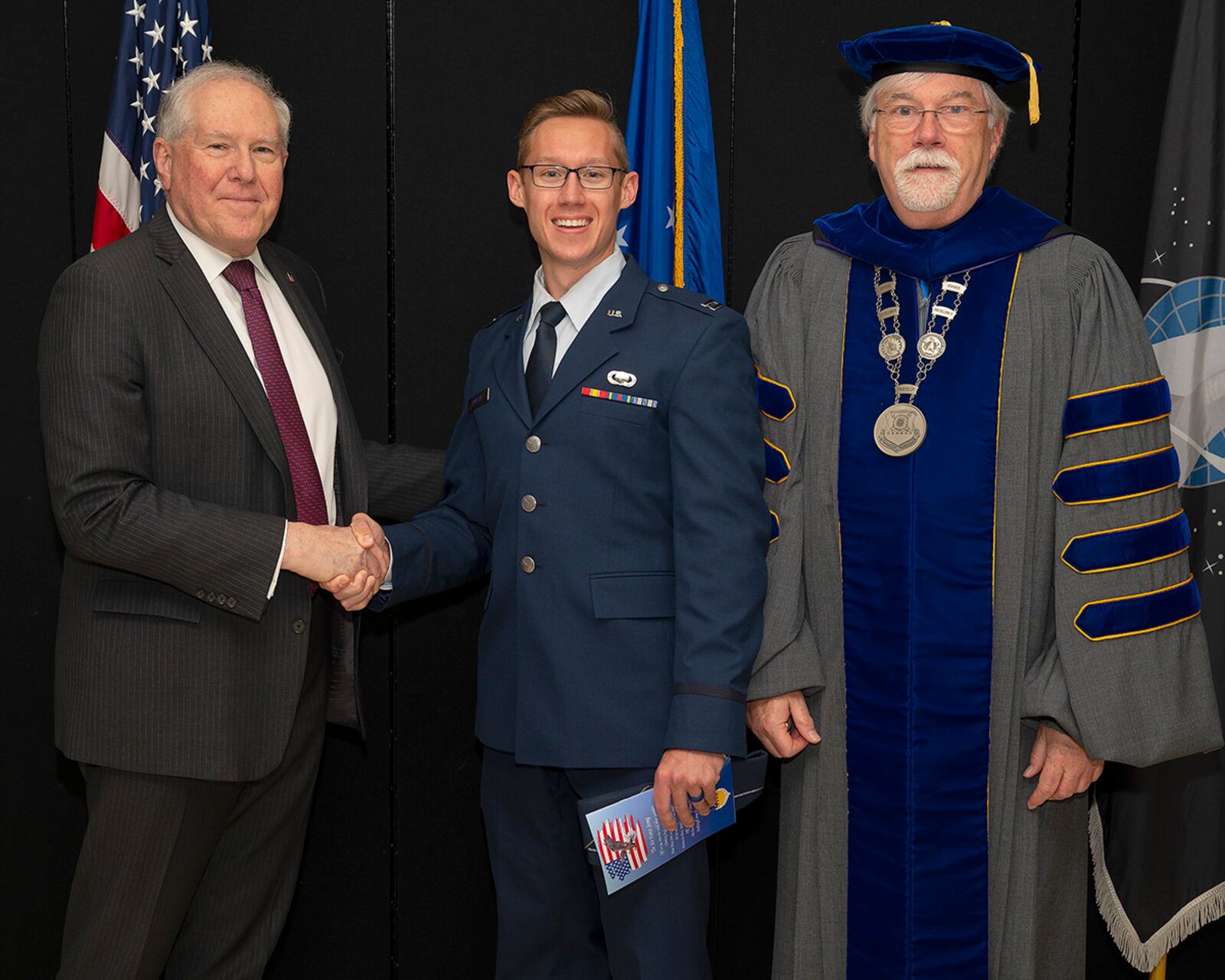 Secretary of the Air Force Frank Kendall presents a coin to a distinguished graduate prior to the Air Force Institute of Technology graduation ceremony in the National Museum of the U.S. Air Force at Wright-Patterson Air Force Base on March 24. Dr. Walter Jones, AFIT director and chancellor, joined Kendall in recognizing the distinguished graduates. U.S. AIR FORCE PHOTO/R.J. ORIEZ