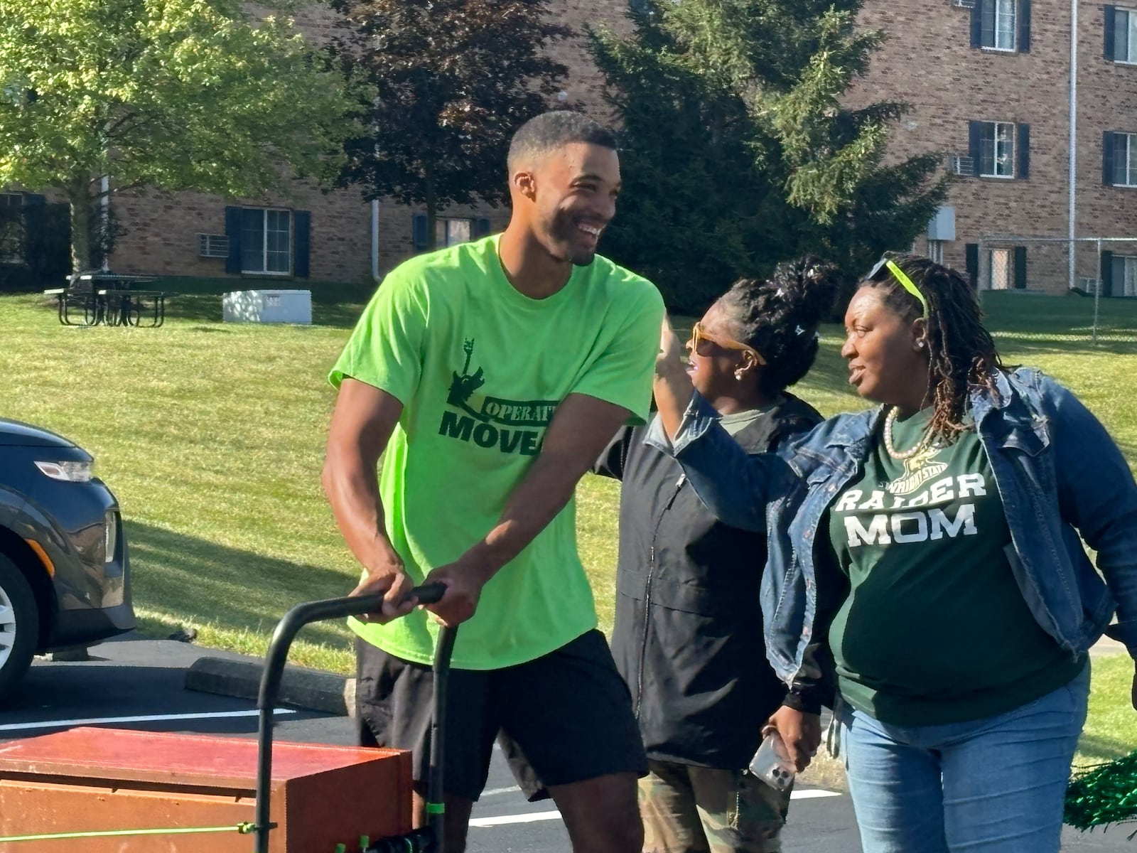 Volunteers helped unload cars and move students into residence halls as Debra Radford, left and Franchesca Alford, right, cheered for them on Wednesday morning. Eileen McClory/ staff